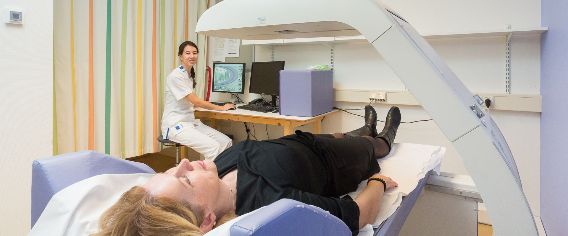 Patiënt gaat onder toezicht van een medewerker door een scan