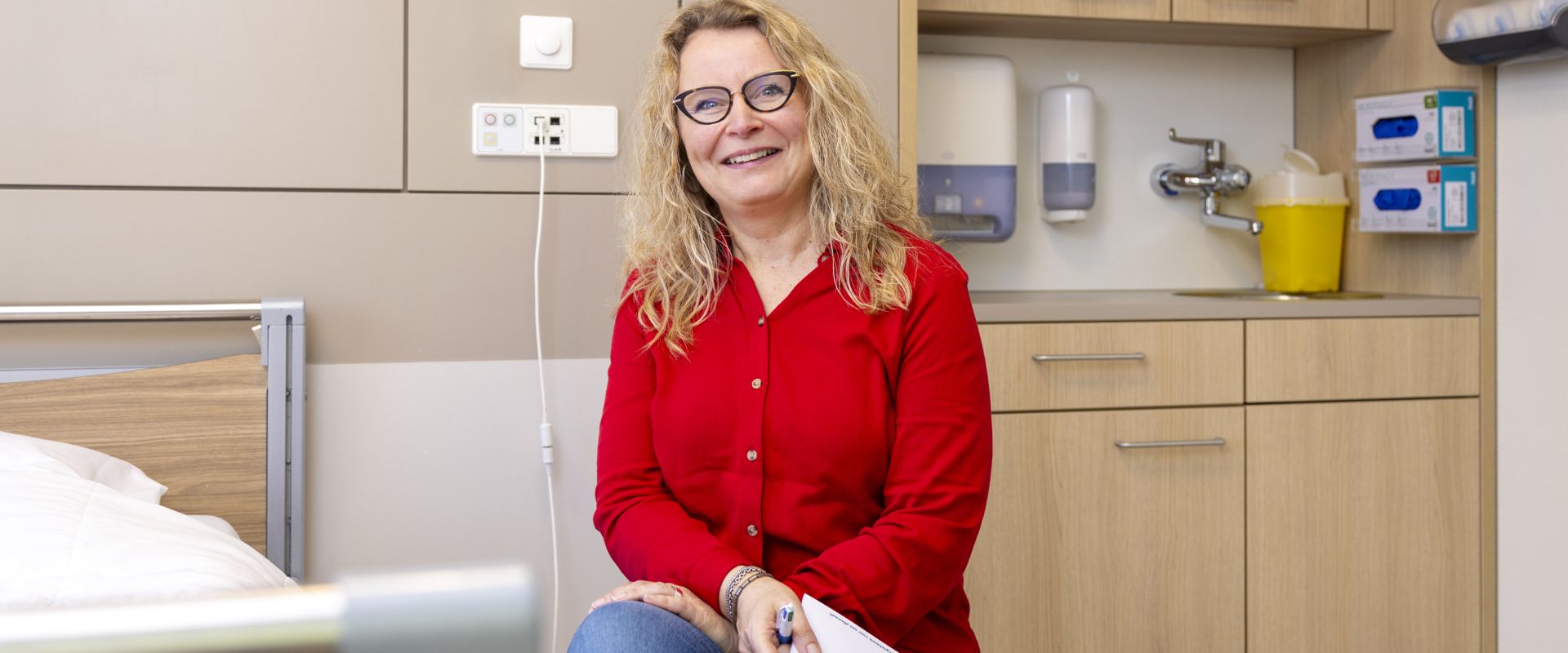 Transferverpleegkundige zit naast het bed van een patiënt