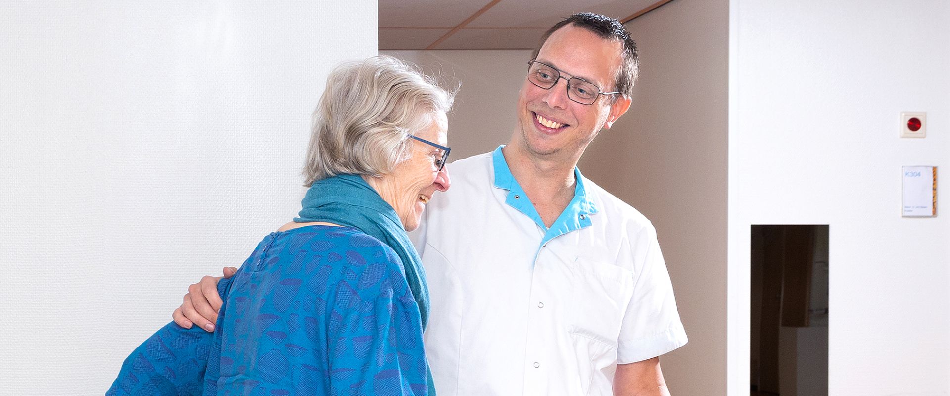 Zorgprofessional helpt cliënt met beweegoefening