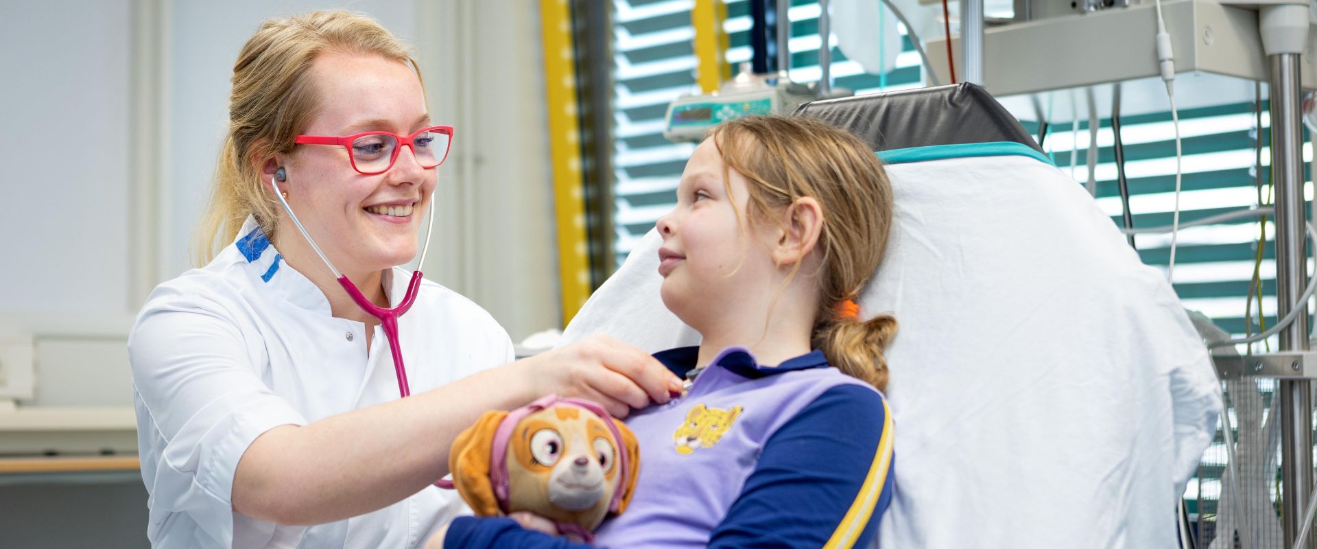 Kind houdt haar knuffel vast en krijgt onderzoek van een arts op bed