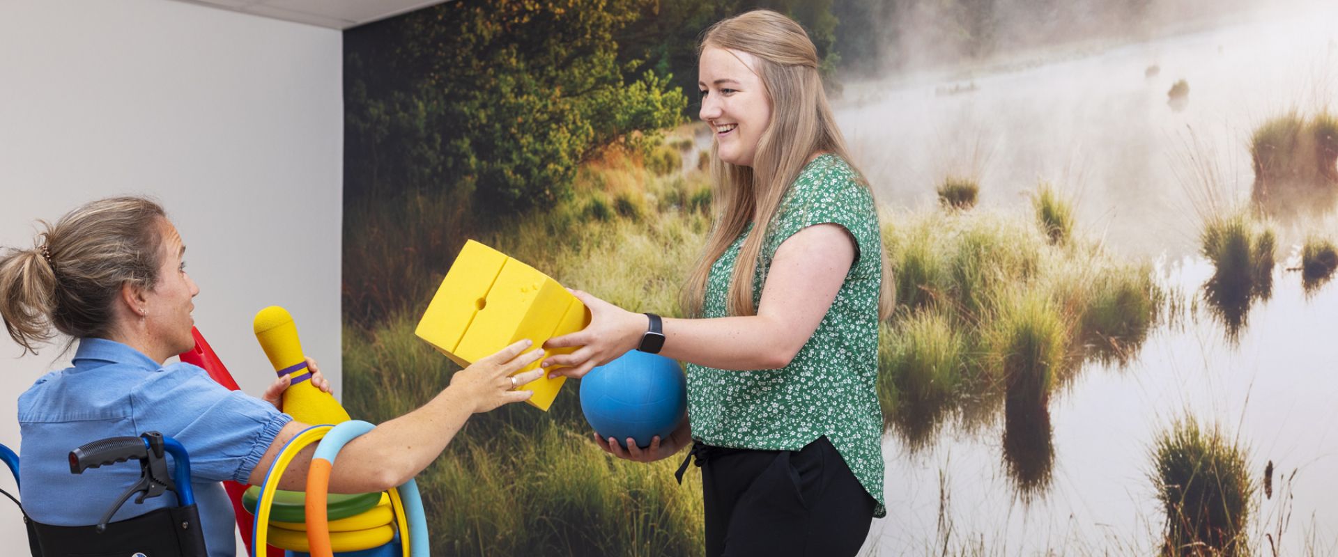 Cliënt in rolstoel doet sportactiviteit met therapeut