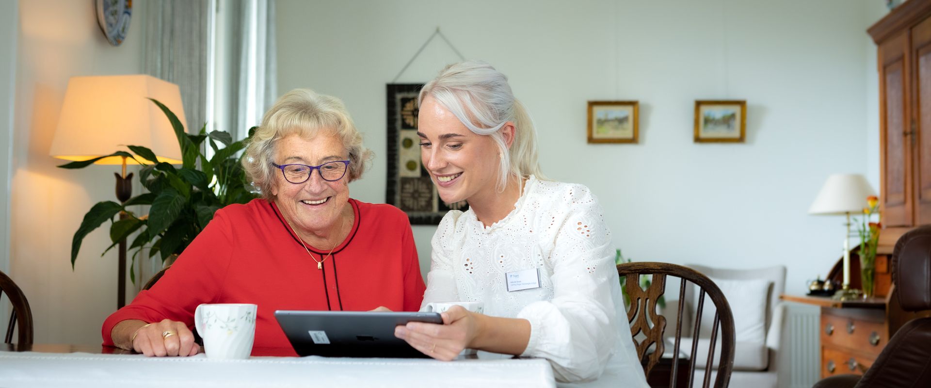 Zorgmedewerker en cliënt kijken samen op een tablet