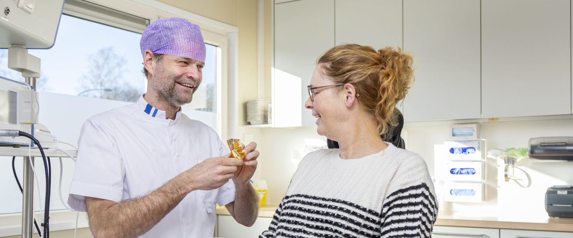 Arts laat een nep gebit aan patiënt zien