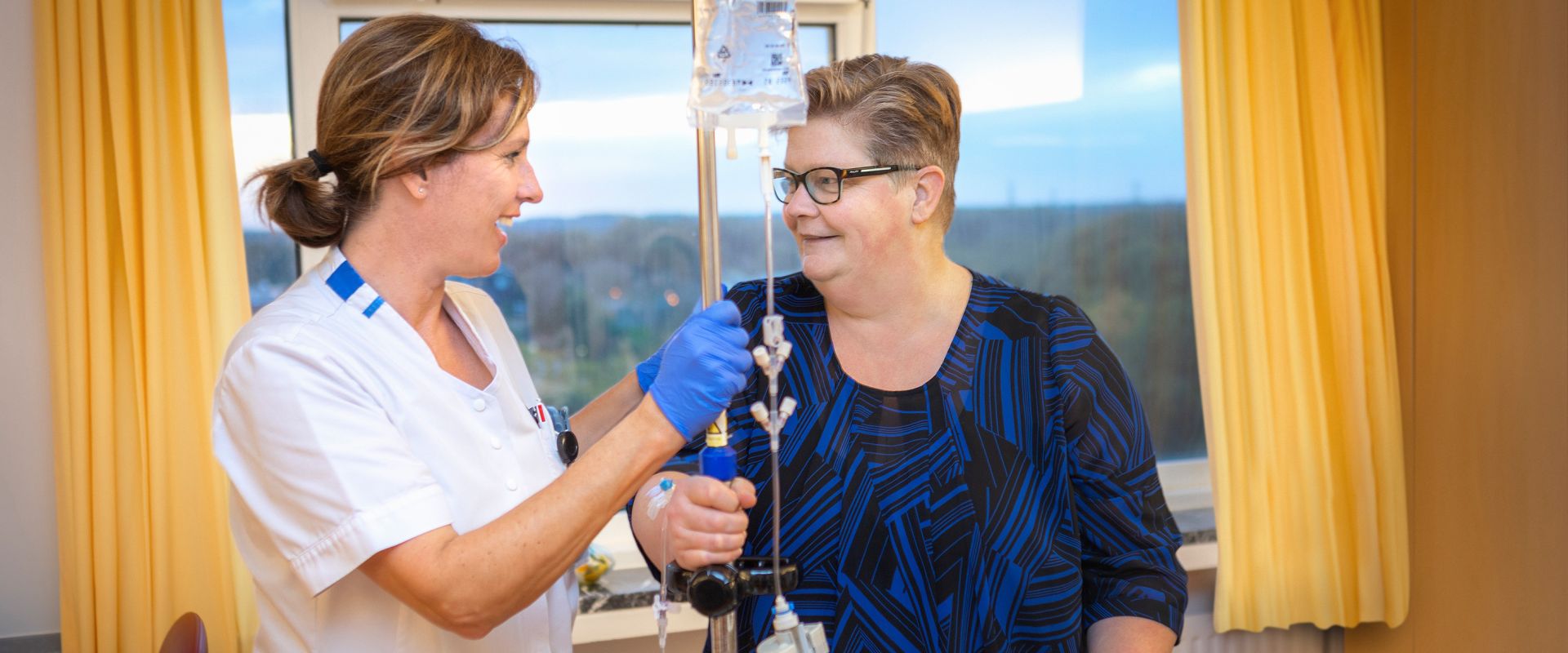 Verpleegkundige en patiënt staan bij het infuus