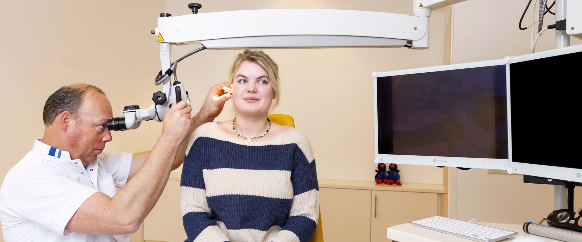 Arts kijkt met medische apparatuur in het oor van een patiënt