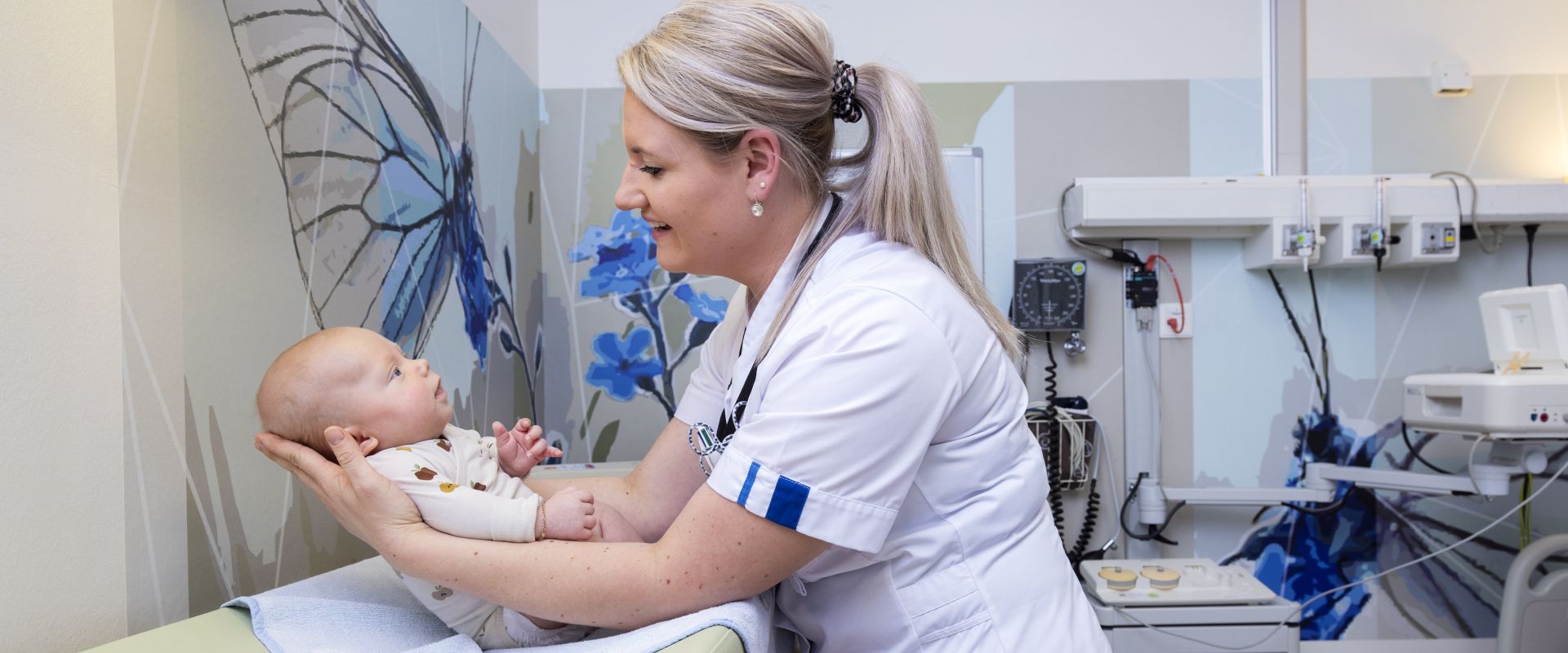 Zorgmedewerker houdt baby vast op het aankleedkussen