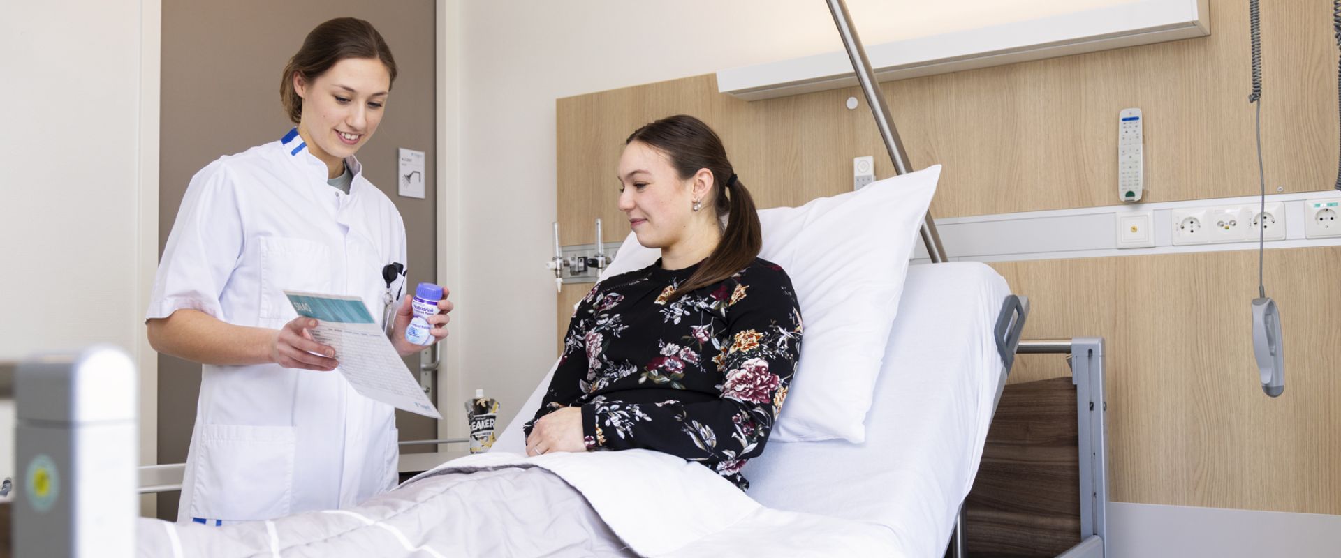 Diëtist geeft instructies aan een patiënt die in bed ligt