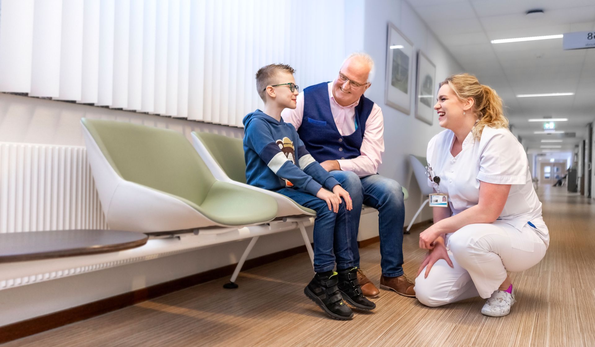 Een opa en zijn kleinzoon zijn in gesprek met een zorgmedewerker