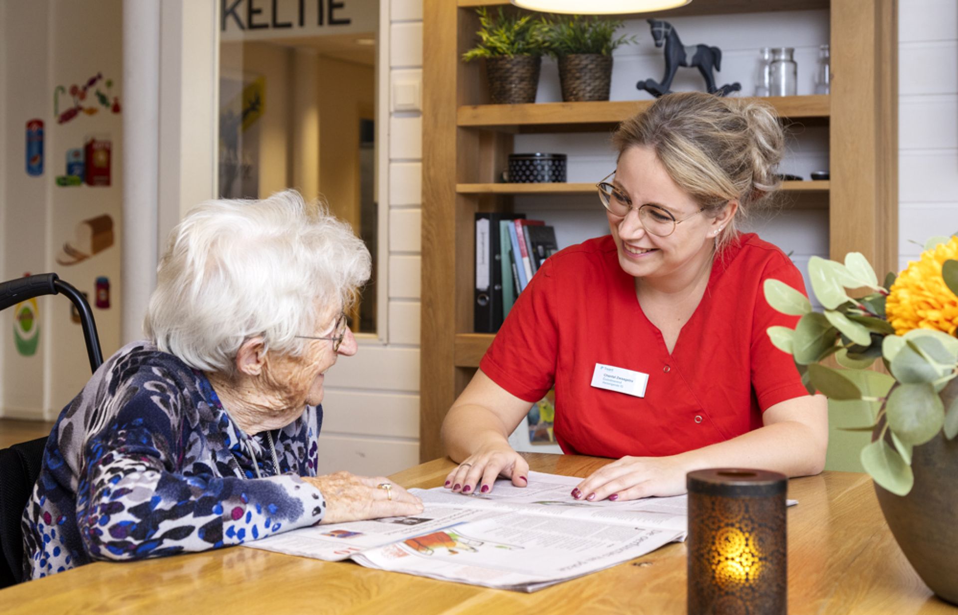 Clënt en medewerker lezen samen de krant in Het Ellertsveld