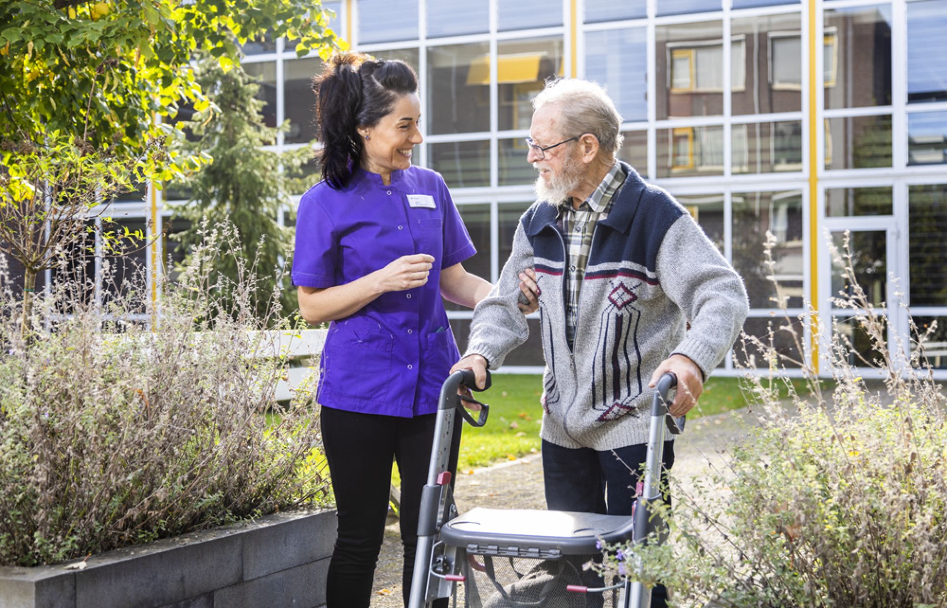 Medewerker en cliën wandelen samen door de tuin van Holtingerhof
