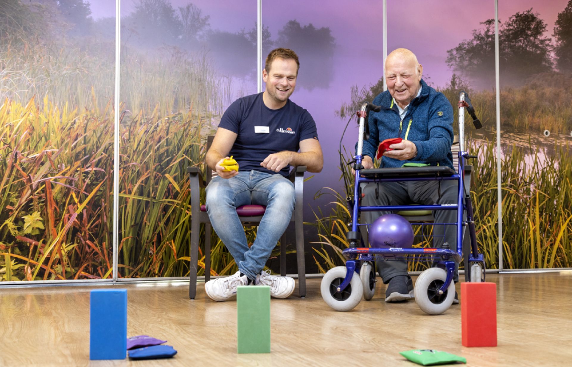 Bewegingsagoog doet samen met een cliënt oefeningen met pittenzakken en blokken