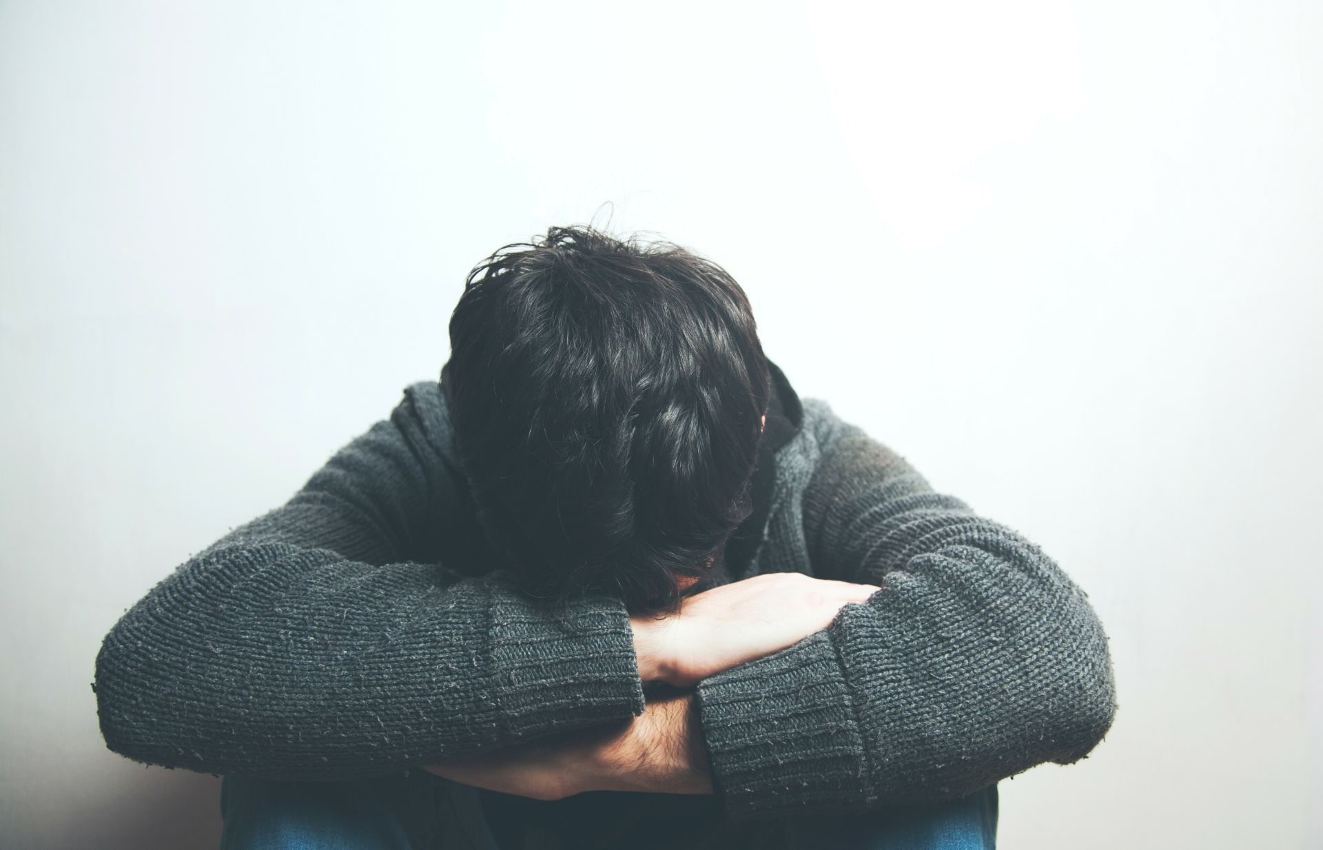 Jongen zit bedroefd met zijn hoofd tussen zijn benen