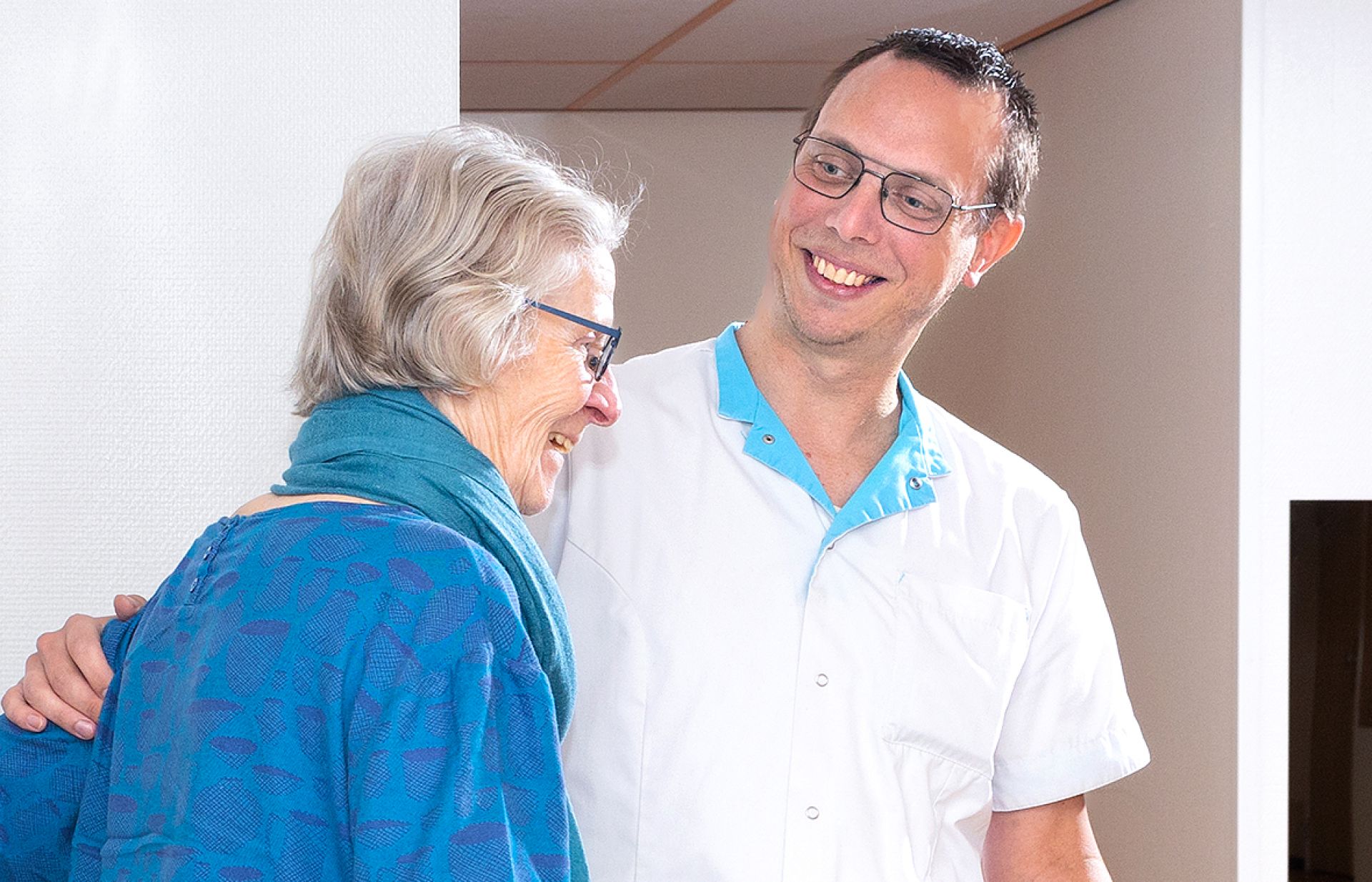 Zorgprofessional helpt cliënt met beweegoefening