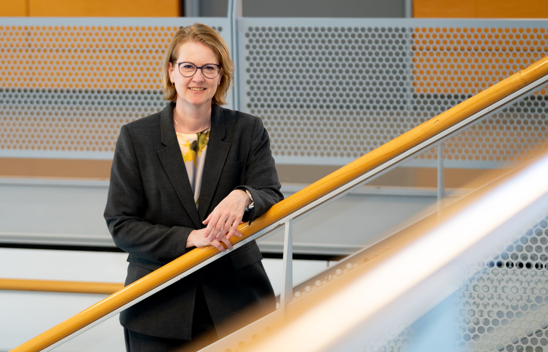 Een vrouw bij een balustrade in een moderne kantooromgeving.