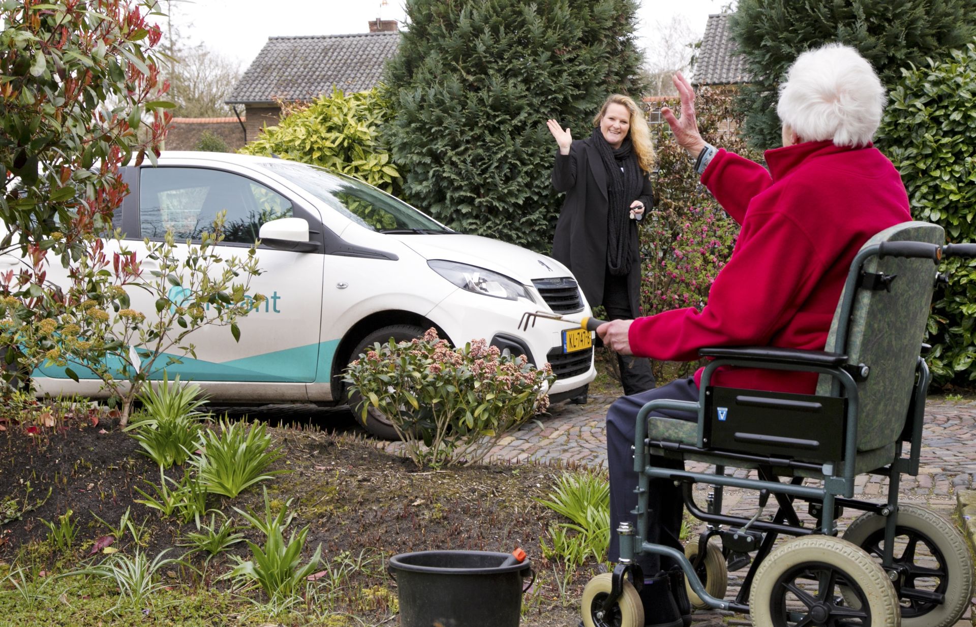 Mevrouw in rolstoel zwaait naar zorgmedewerker Treant