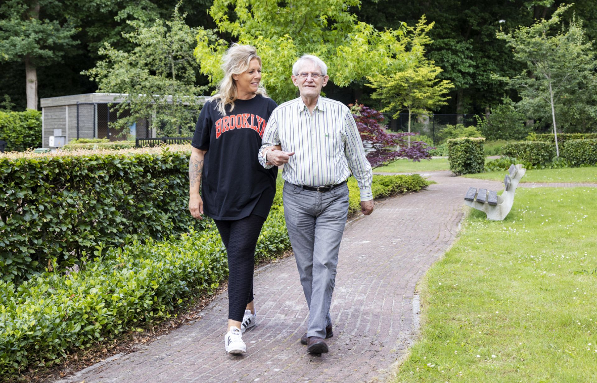 Bewoner wandelt met medewerker een rondje om Tonckenshuys.