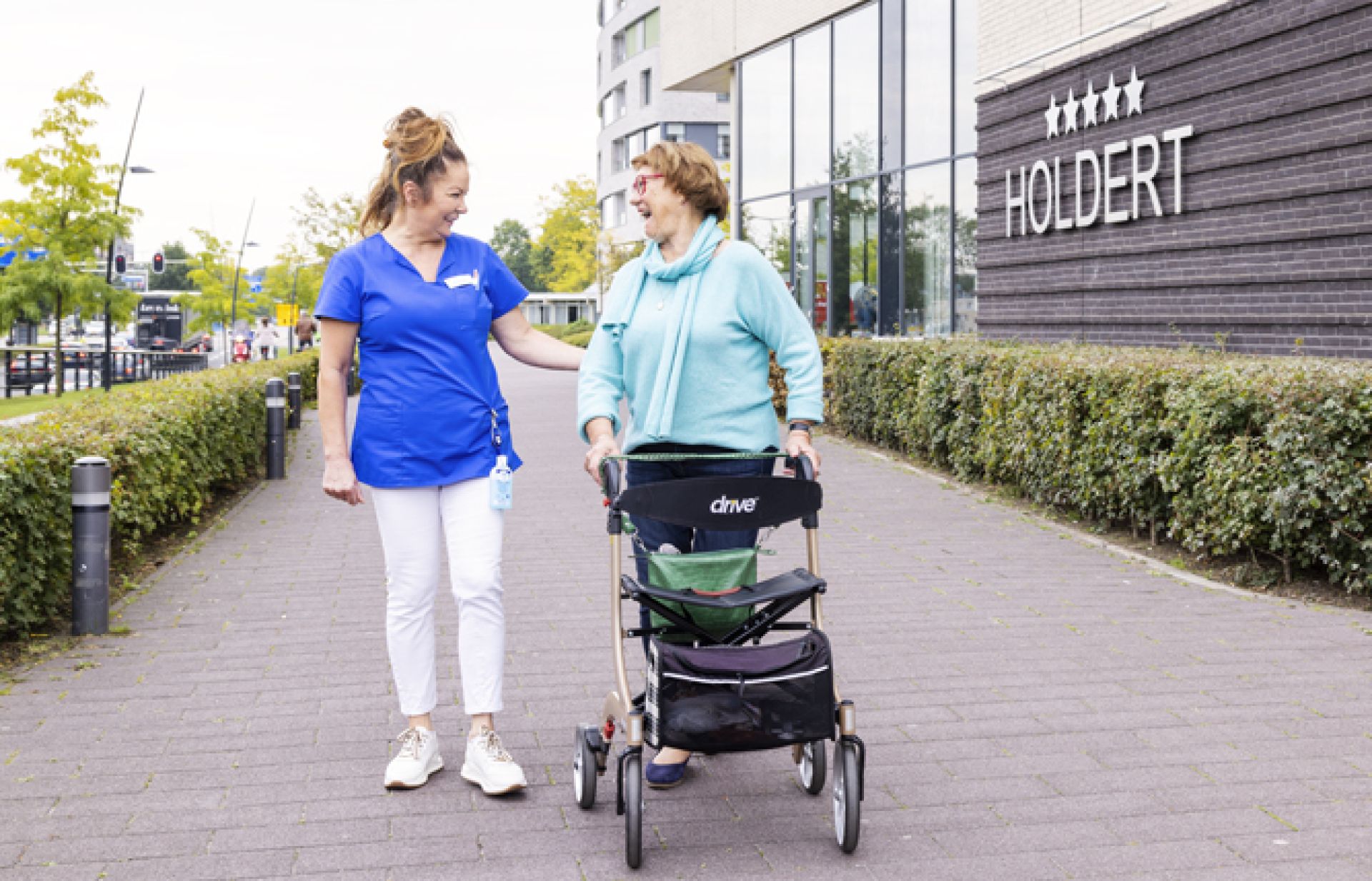 Holdert bewoner en medewerker wandelen samen buiten