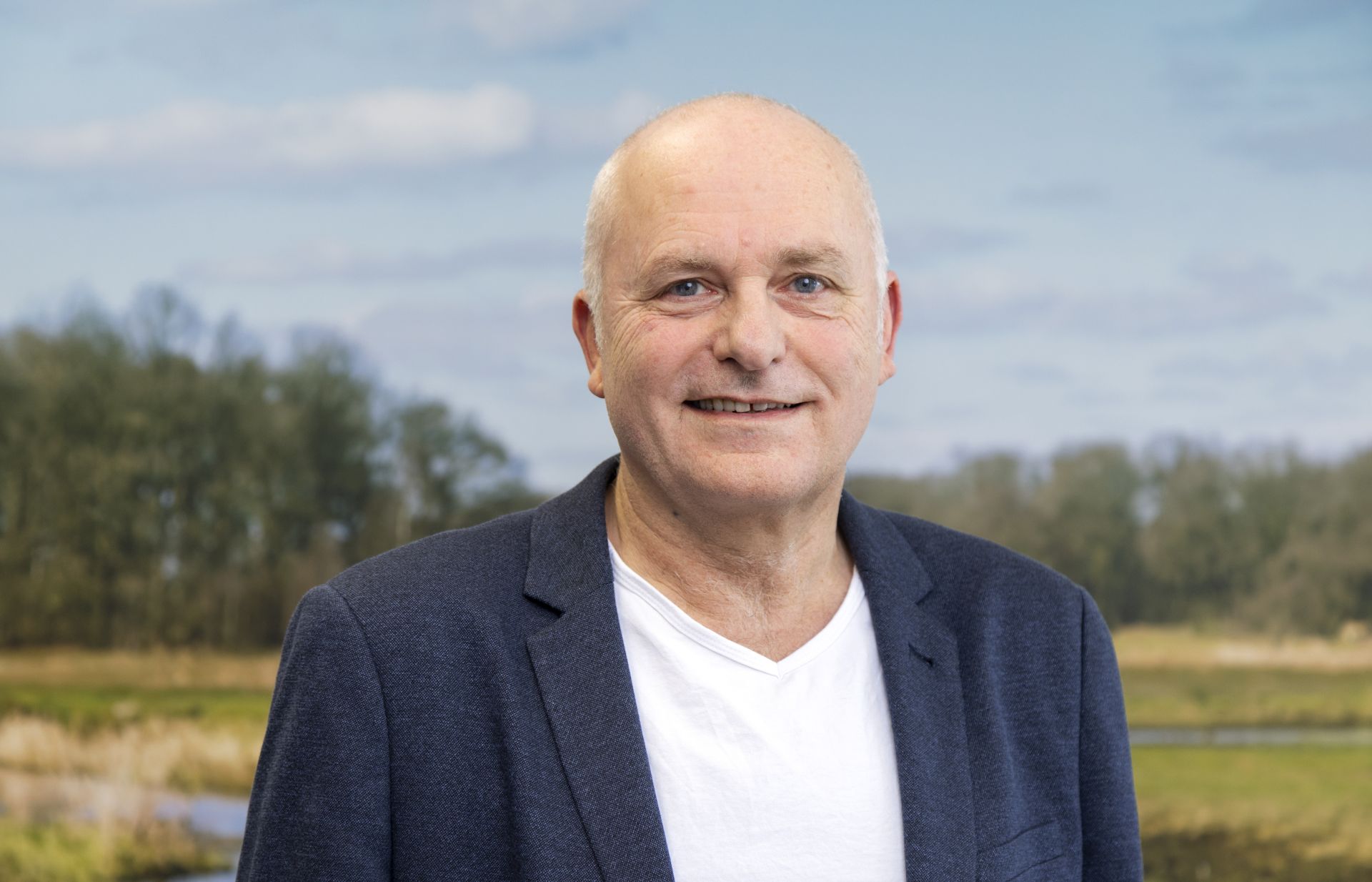 Een persoon staat voor een poster met een natuurlijk landschap.