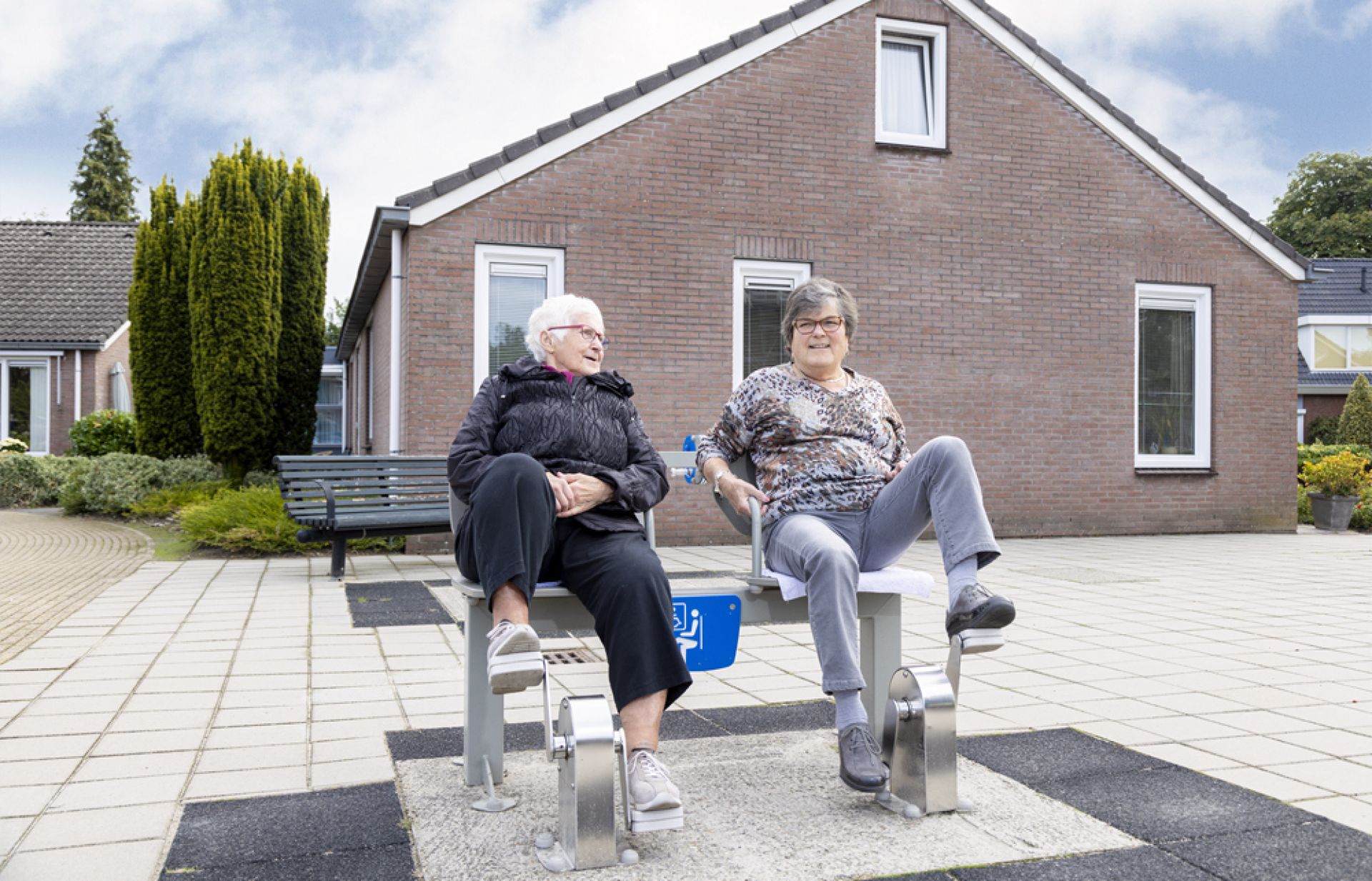 Medewerker en bewoner zijn samen buiten aan het sporten op een soort fiets