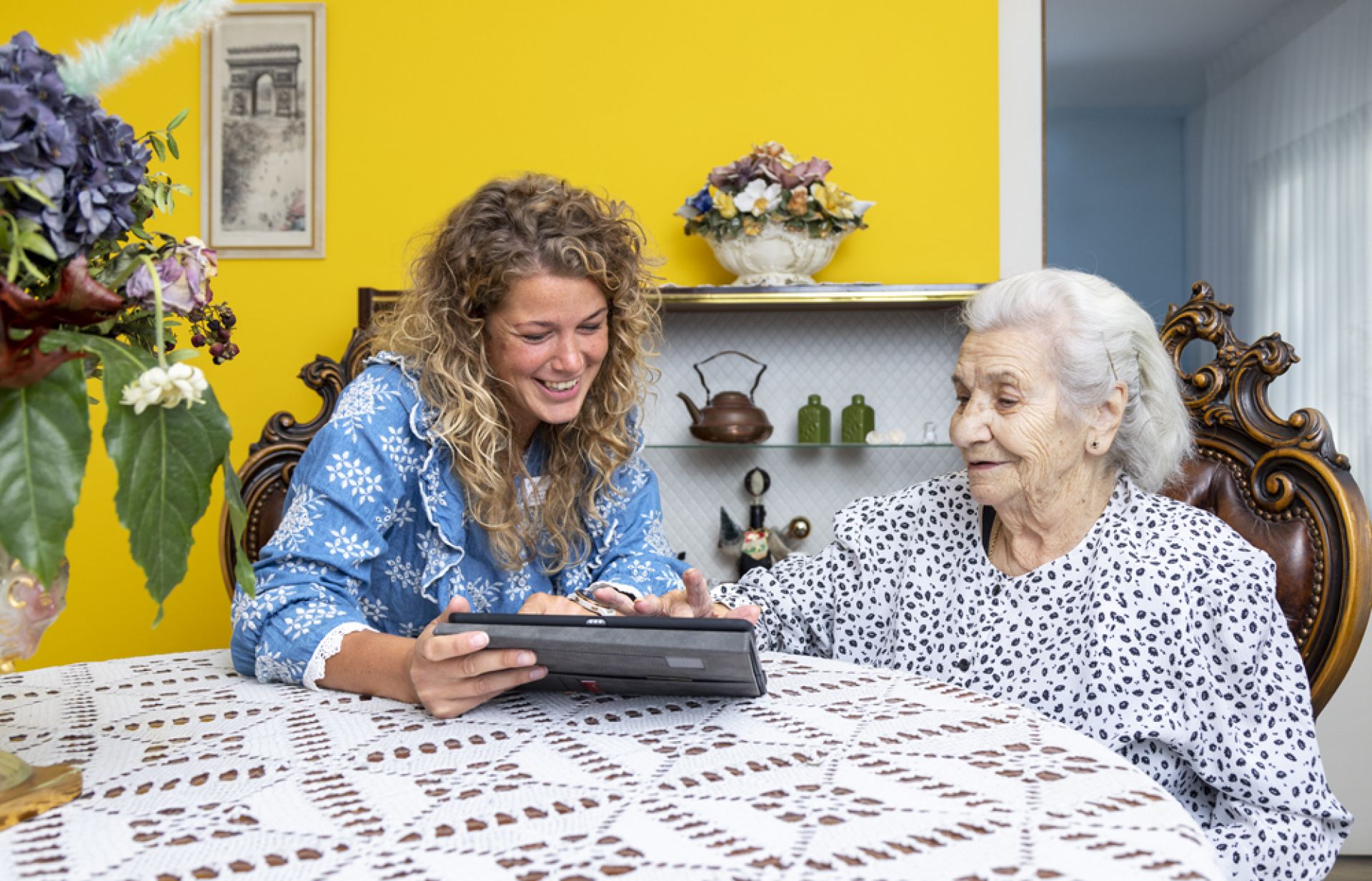 Medewerker en cliënt kijken samen naar IPad.