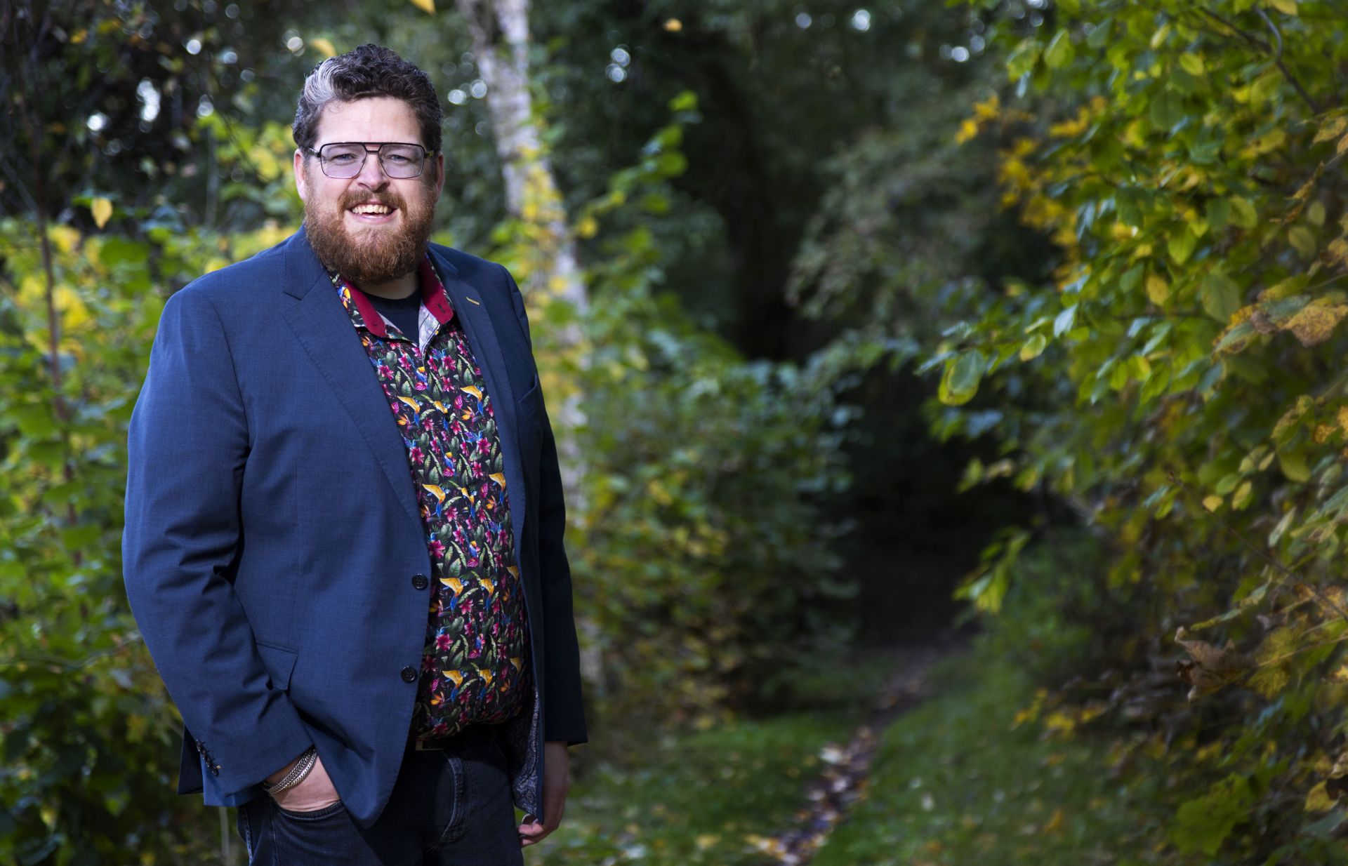 Patiënt Jeroen staat in het bos met zijn handen in zijn zakken