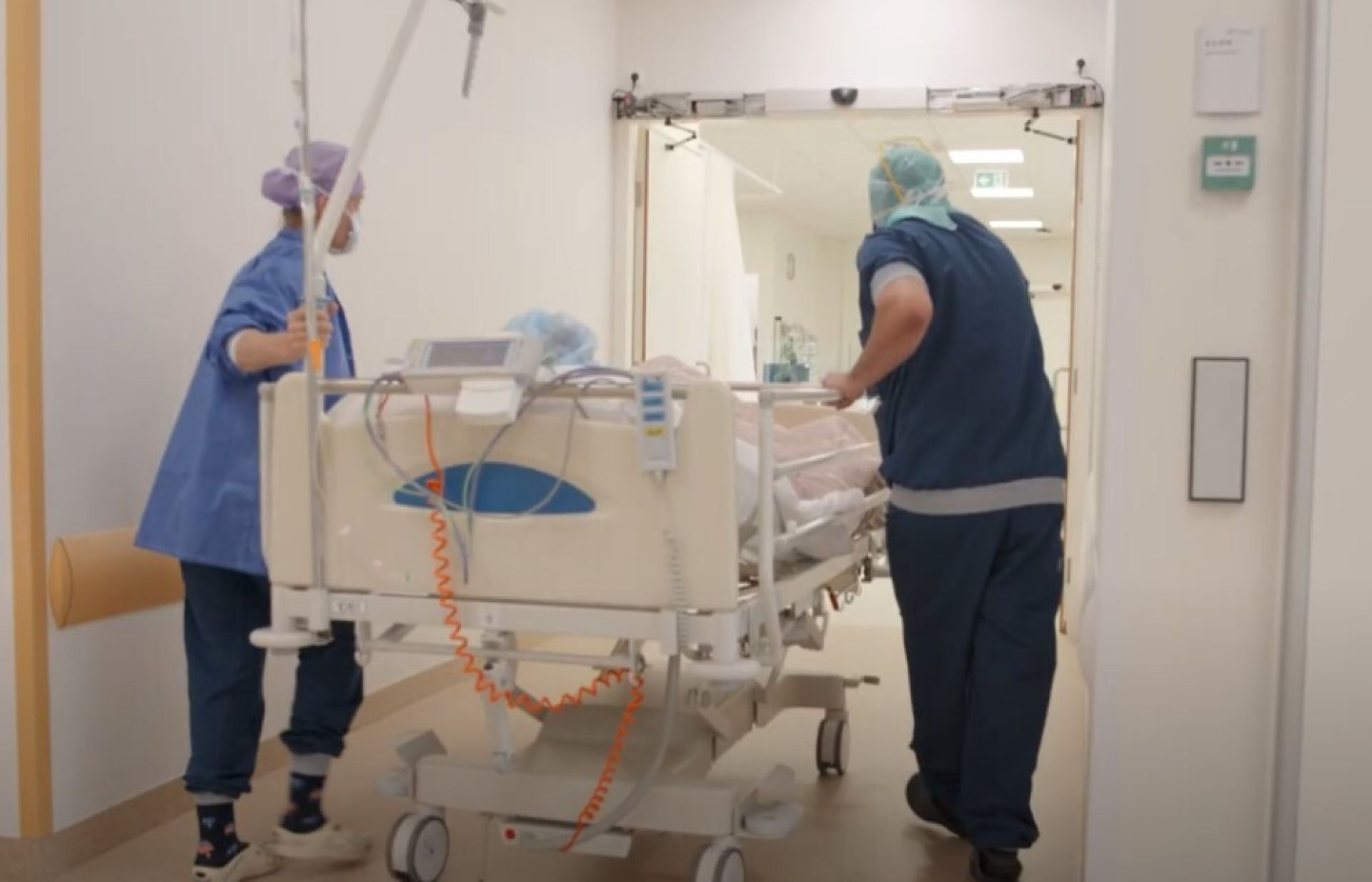Verplegers vervoeren een patiënt in bed