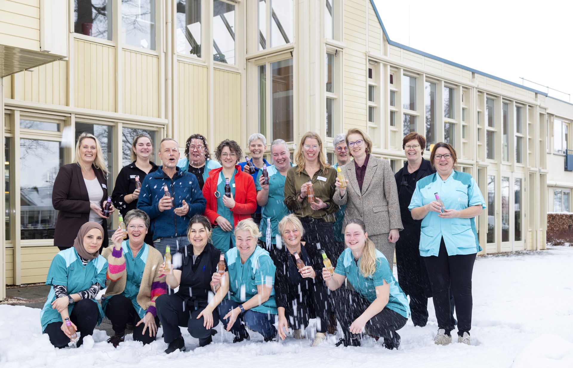 Collega's in de sneeuw genietend van hun nieuwjaarstraktatie: een flesje biologische frisdrank 