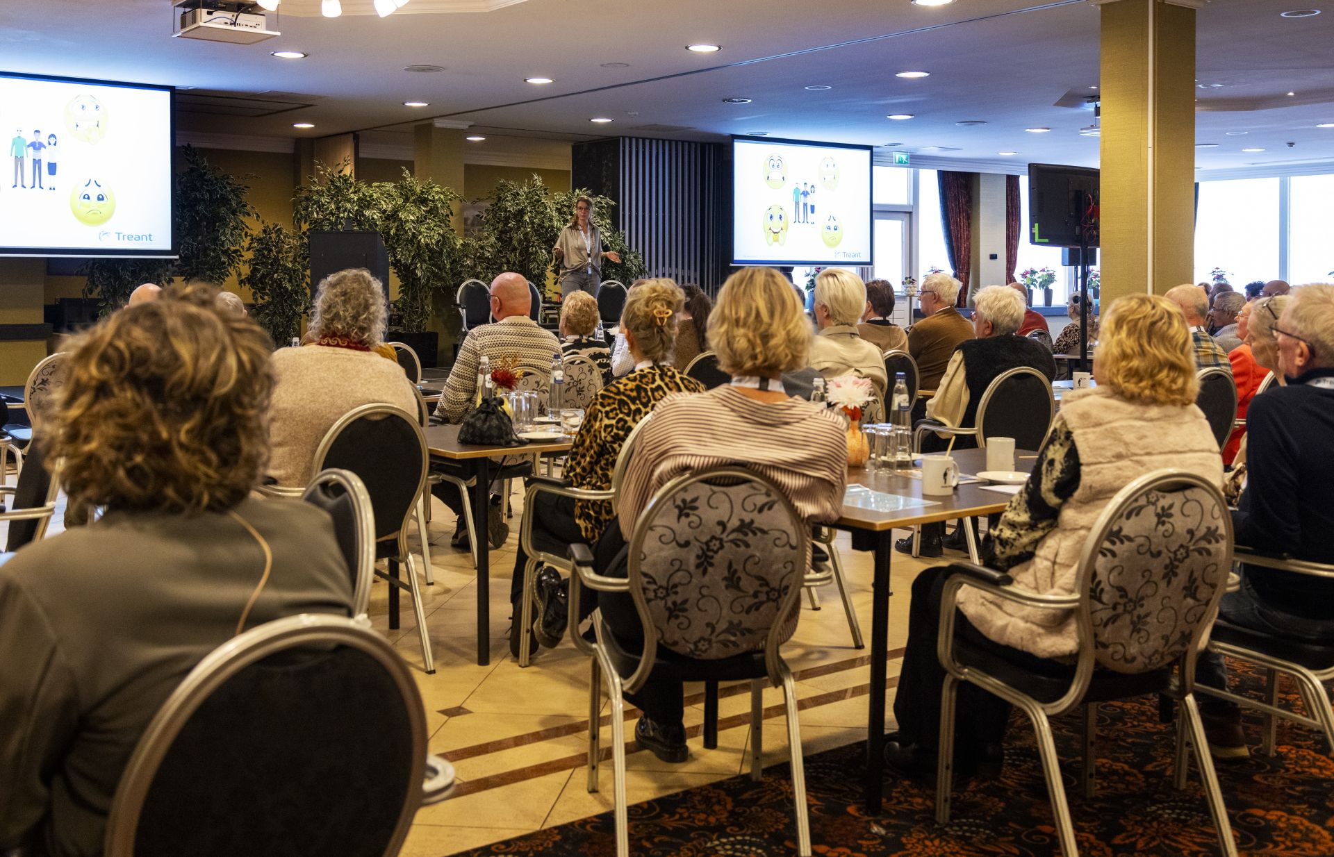 Impressie van de IC-nazorgdag van Treant. ex-IC-patiënten luisteren naar spreker op podium