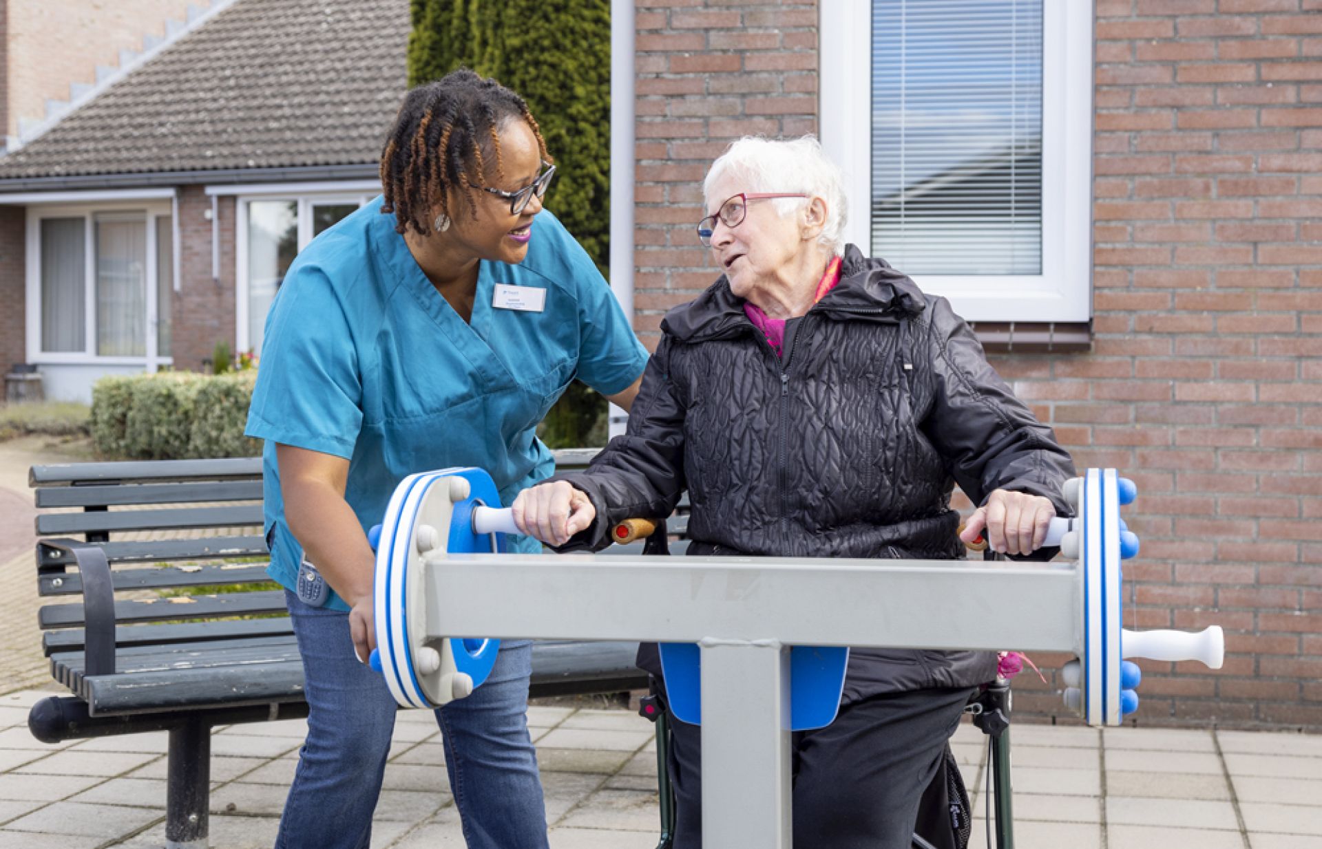 Een medewerker en bewoner zijn buiten bezig met een beweegtoestel