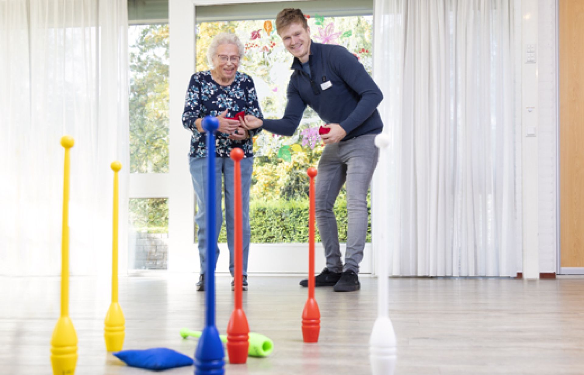 Medewerker en cliënt spelen met kegels.