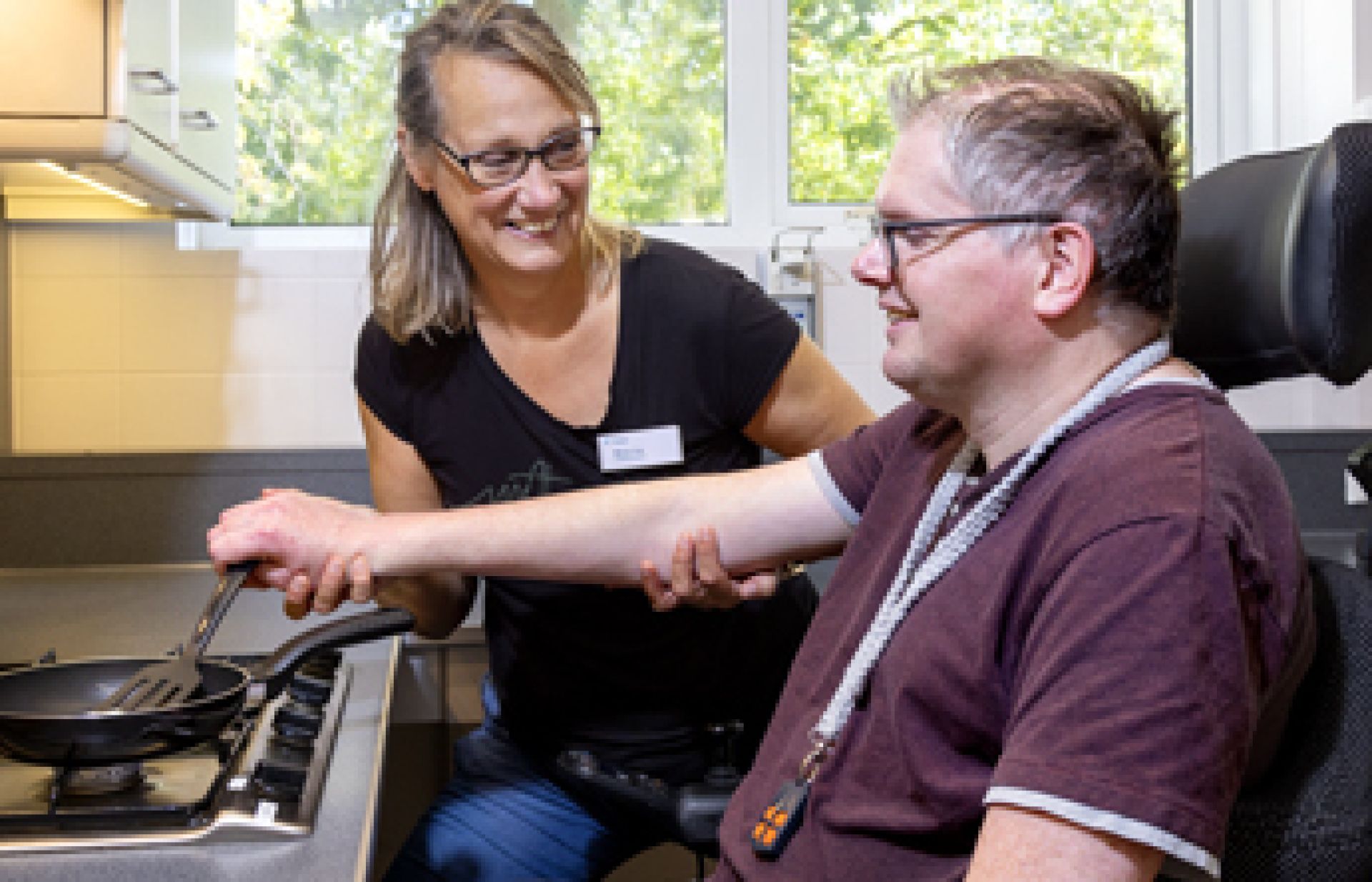 Medewerker helpt cliënt bij het bakken van een eitje.