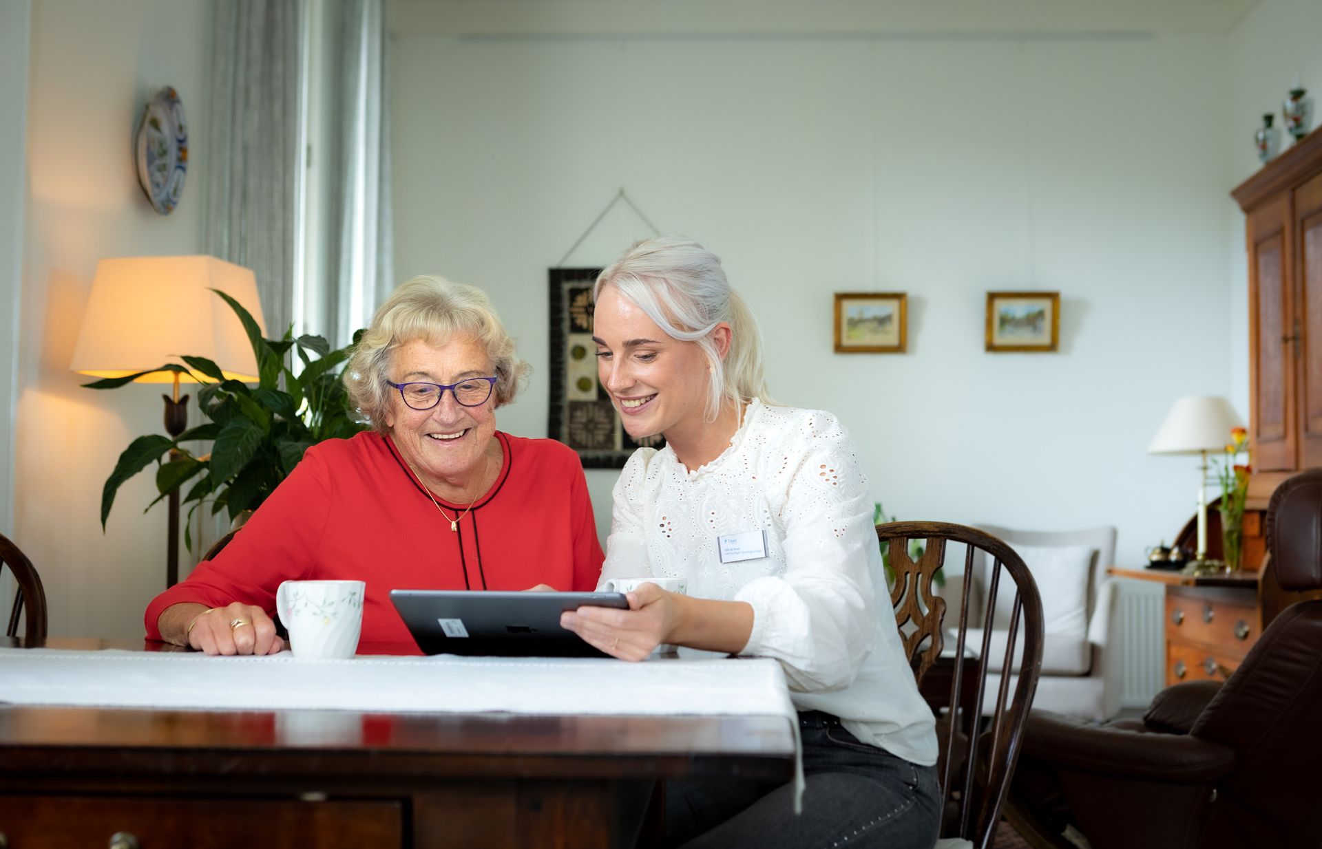 Zorgmedewerker en cliënt kijken samen op een tablet