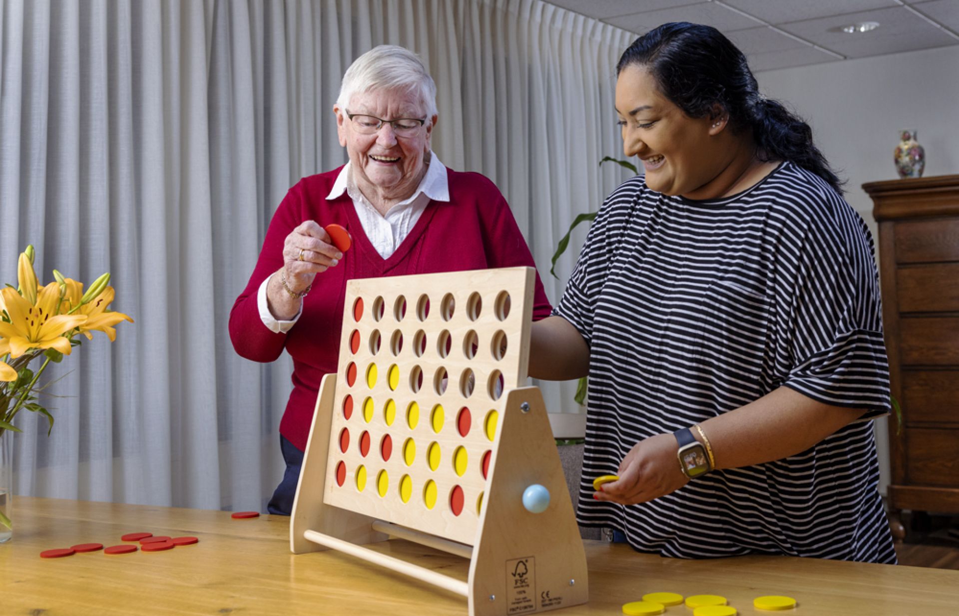 Bewoner en medewerker van Olden Kinholt spelen samen vier op een rij
