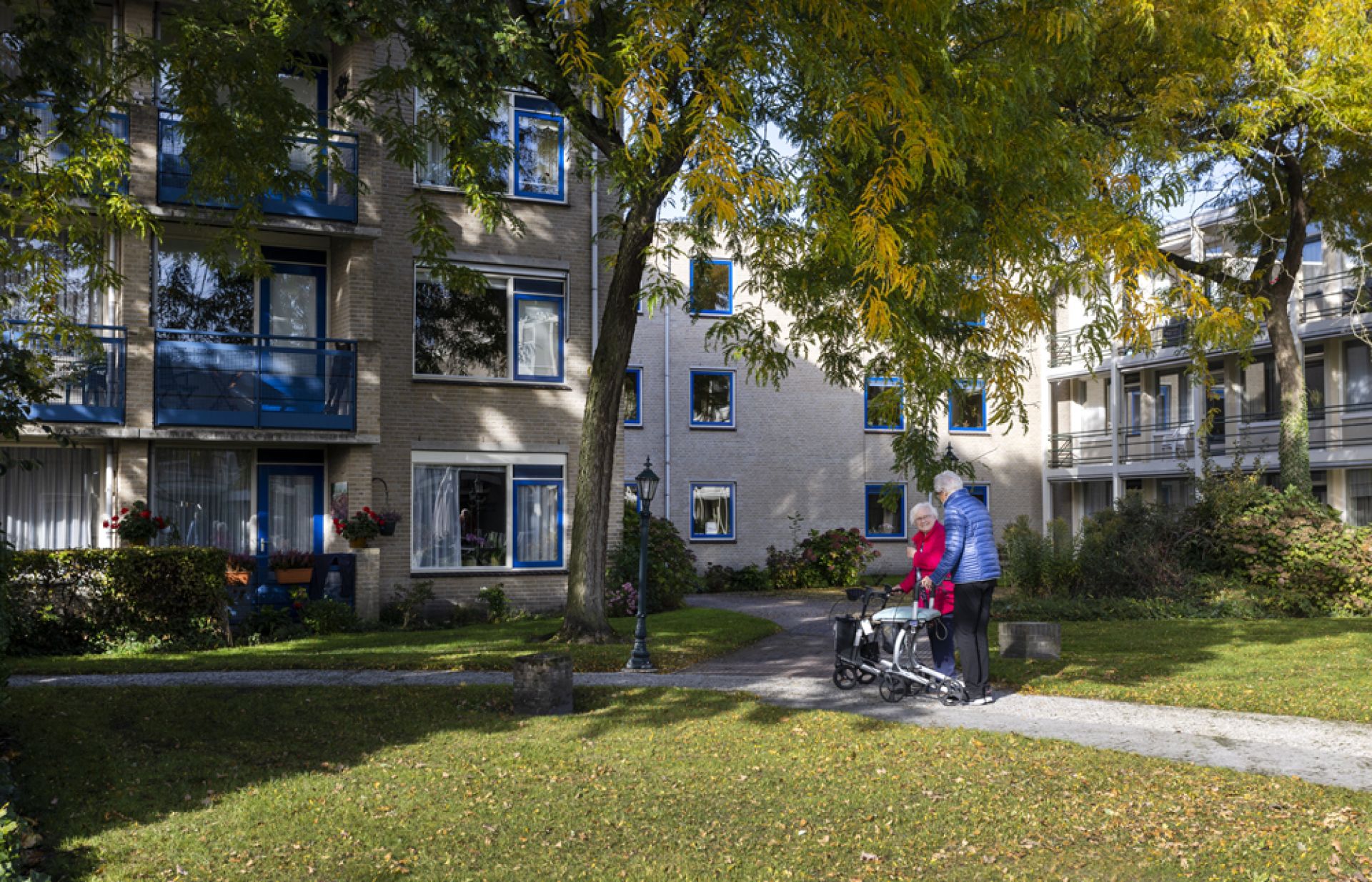 Bewoner van Olden Kinholt loopt samen met de medewerker een rondje om het gebouw.