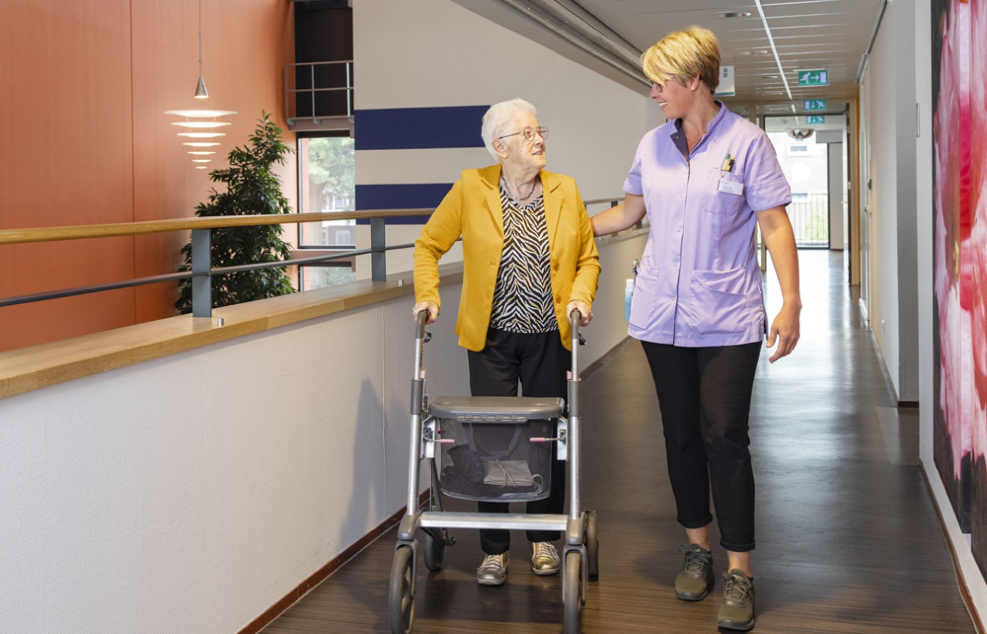 Bewoner van Holdert wantelt samen met medewerker door de gang