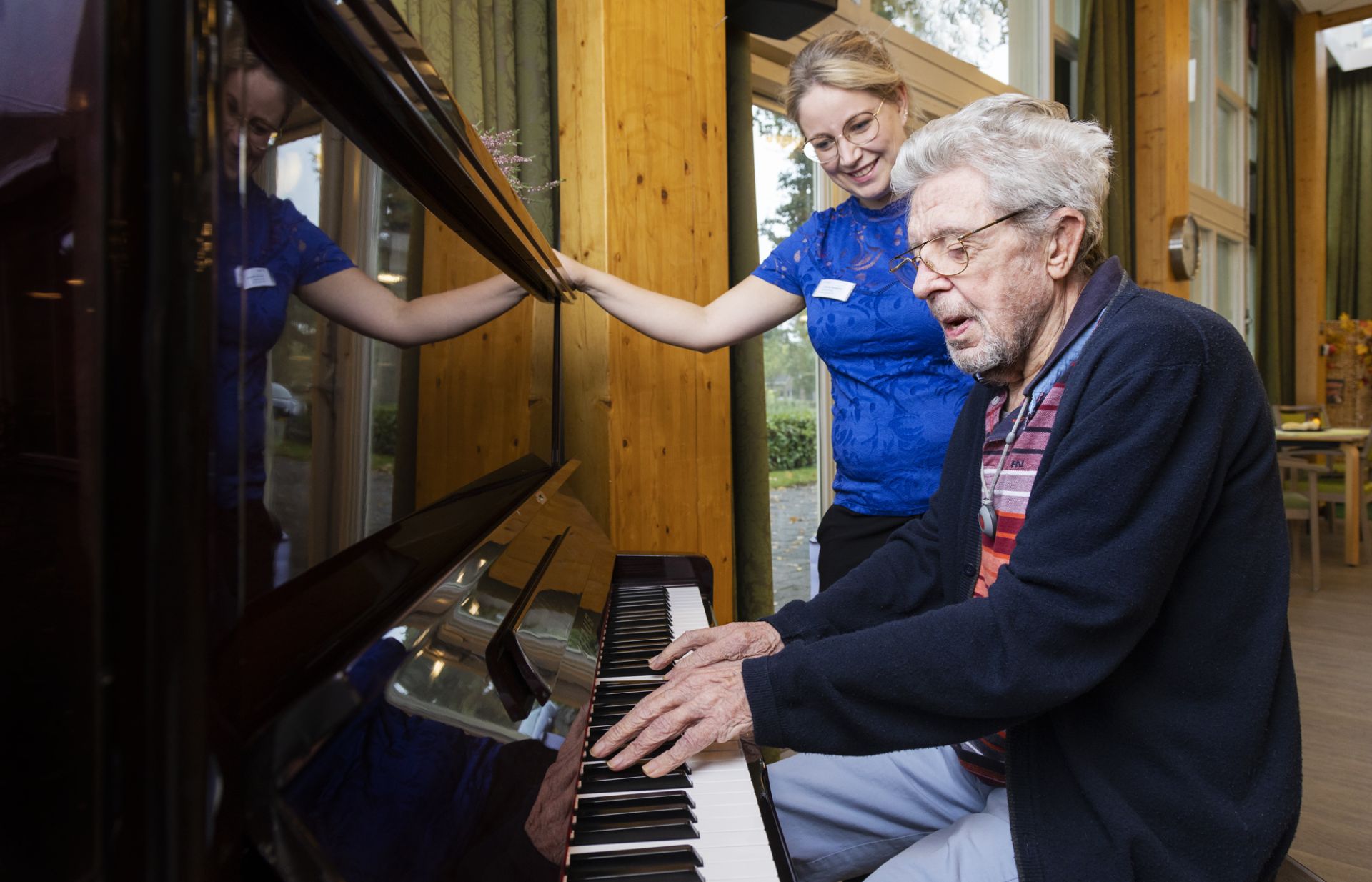 Cliënt speelt onder begeleiding van medeweker een lied op de piano