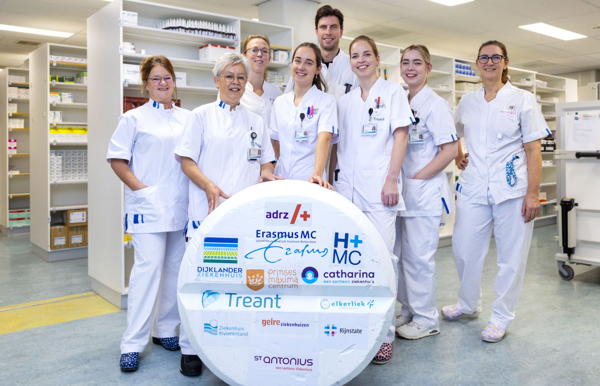 Collega's staan achter een meterhoge paracetamol met daarop logo's van de deelnemende ziekenhuizen