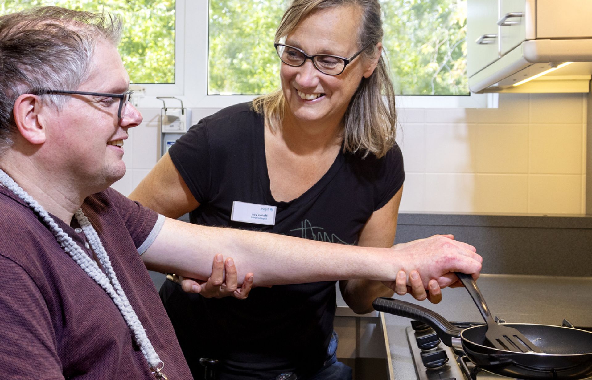 Ergotherapeut helpt cliënt met eitje bakken
