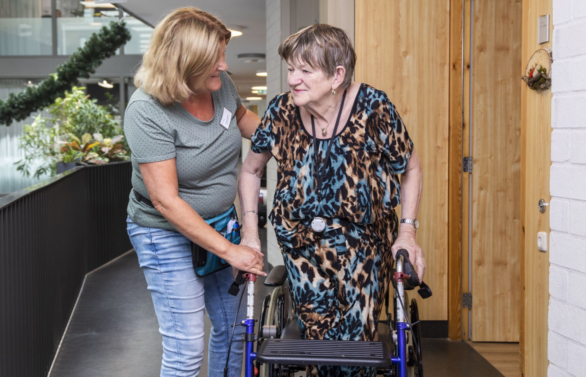 Medewerker helpt bewoner met een rondje lopen in Tonckenshuys.