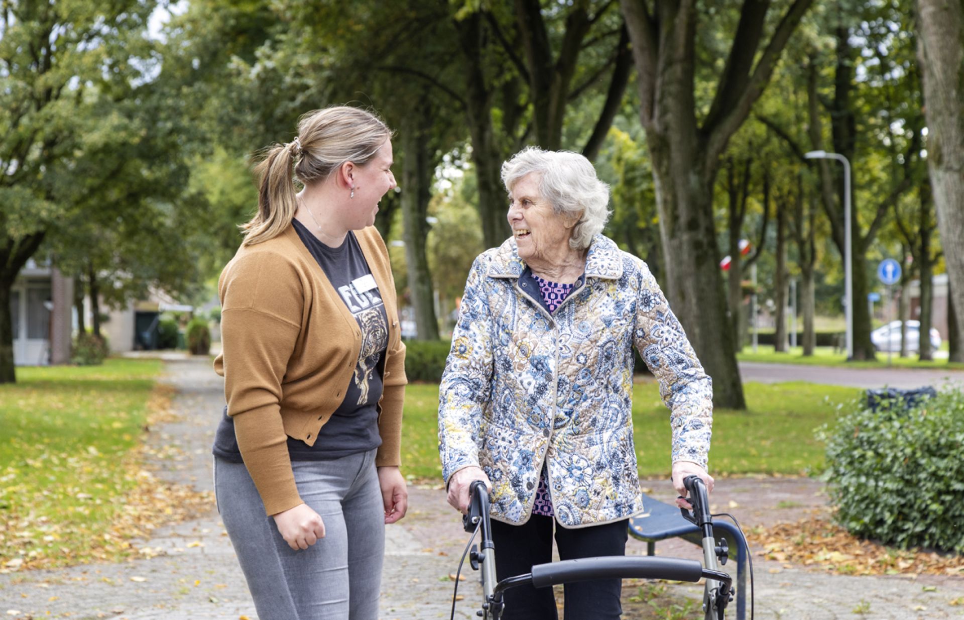 Bewoner loopt samen met medewerker lachend een rondje nabij Selkersgoorn.