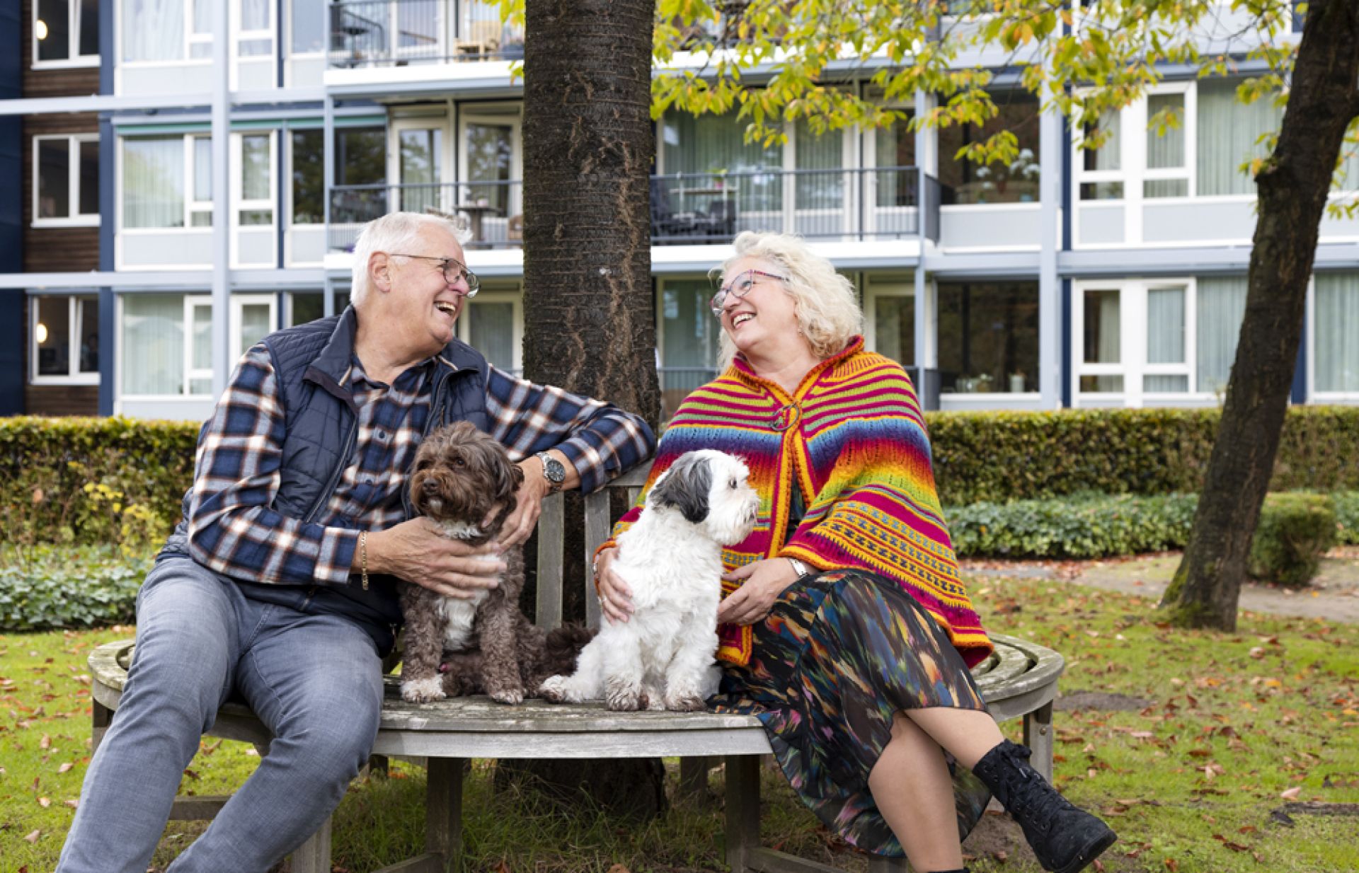 Twee bewoners van Oostermarke zitten buiten op een bankje met hond