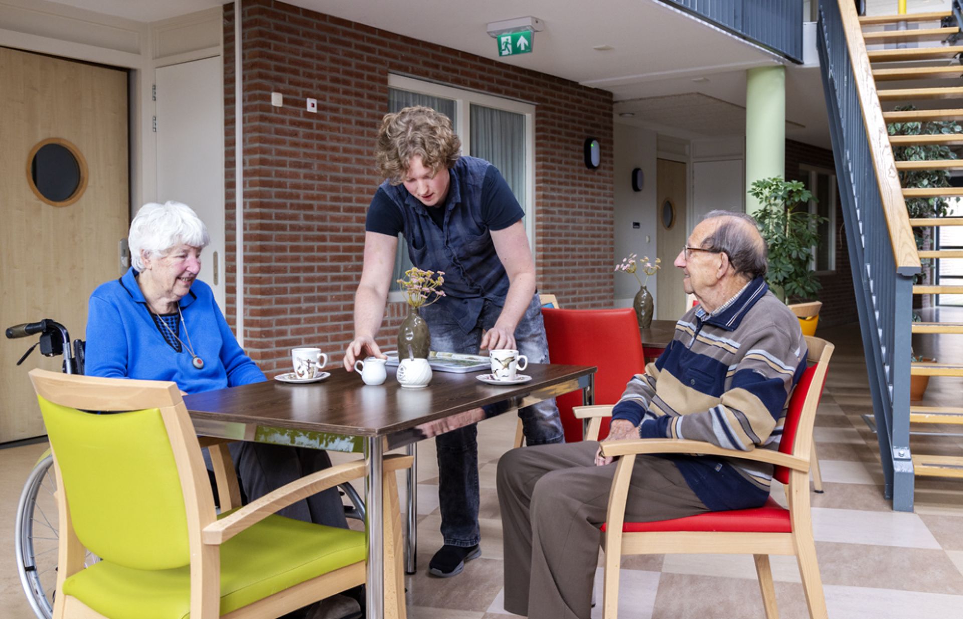 Twee bewoners drinken samen een bakje koffie aan de koffietafel