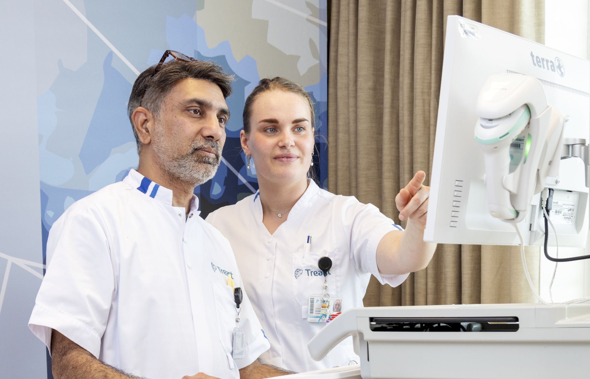 Zorgprofessionals bekijken gegevens op een computer naast een ziekenhuisbed