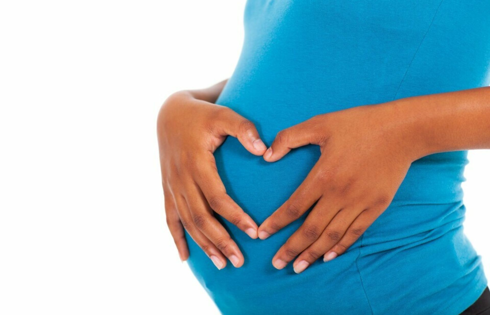 Vrouw met haar handen in hartvorm op zwangere buik