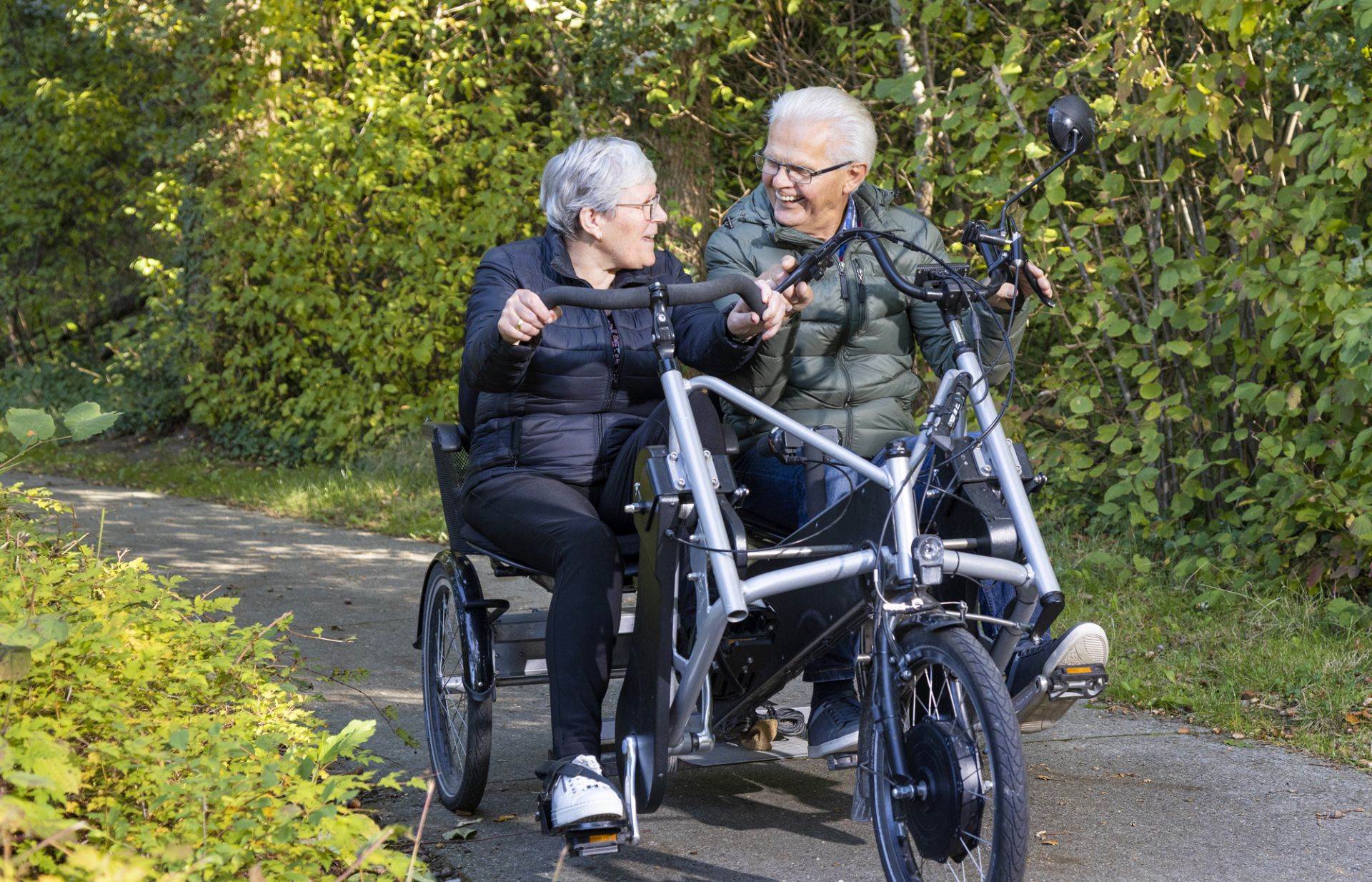Cliënt en vrijwiller fietsen samen door het bos op een duofiets