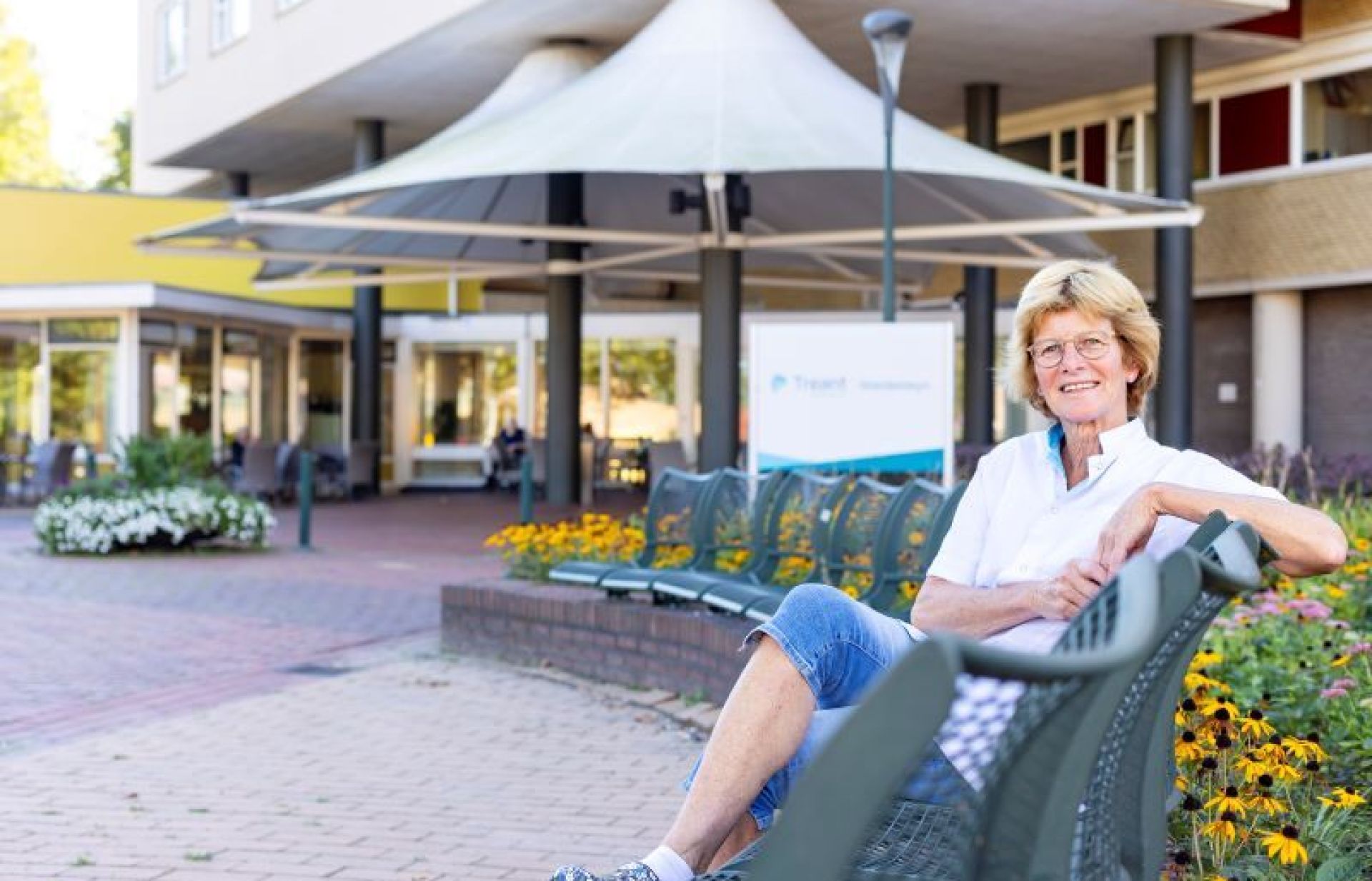 Jenny Hekman zit op het bankje voor woonzorglocatie Weidesteyn