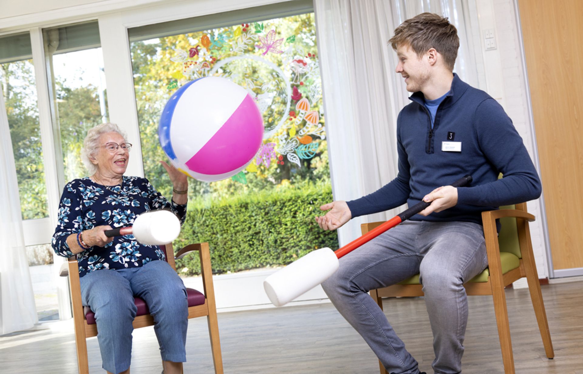 Medewerker en cliënt spelen met een strandbal.