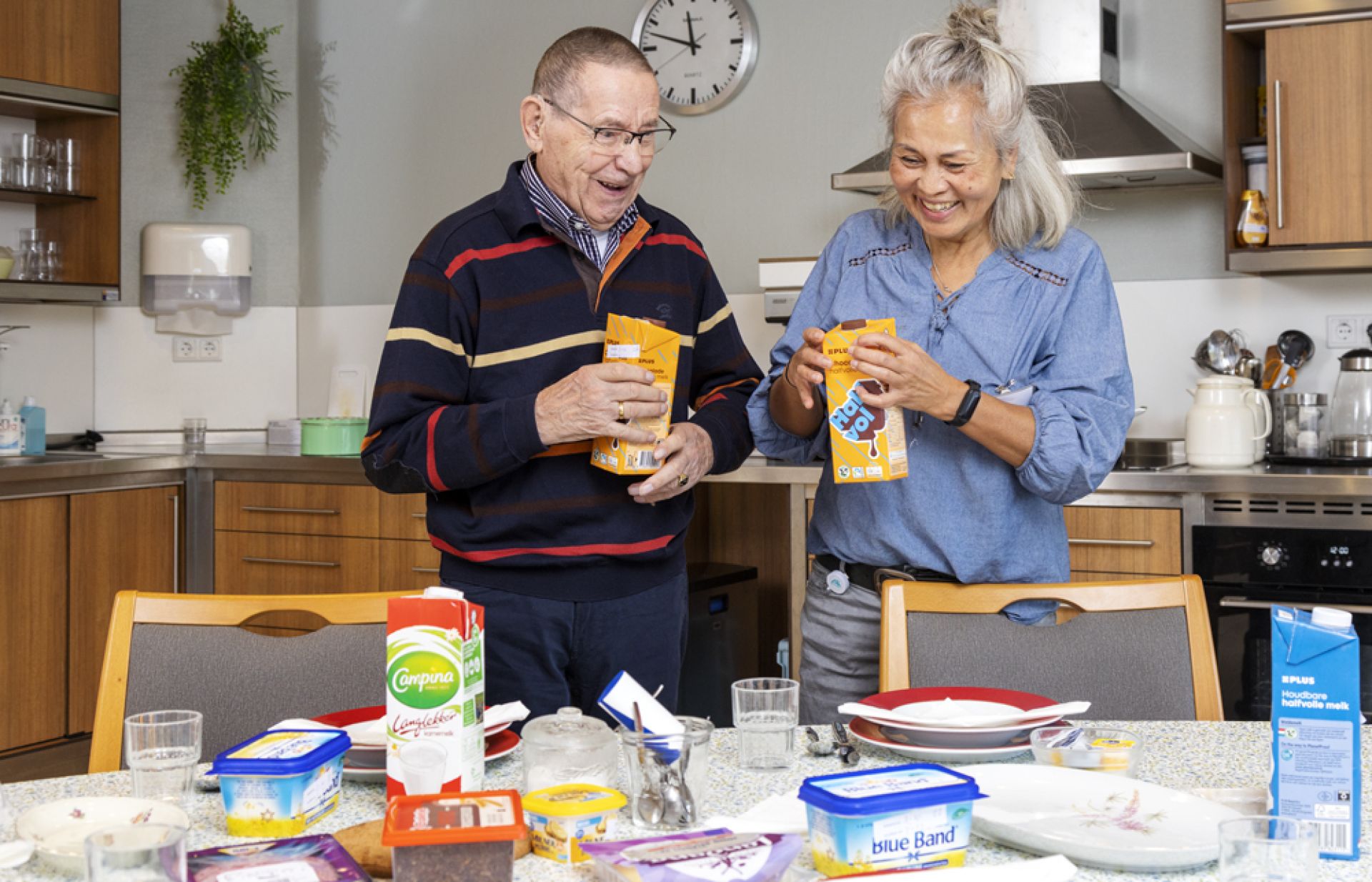 Cliënt dekt samen met een medeweker de tafel en schenkt chocomelk in