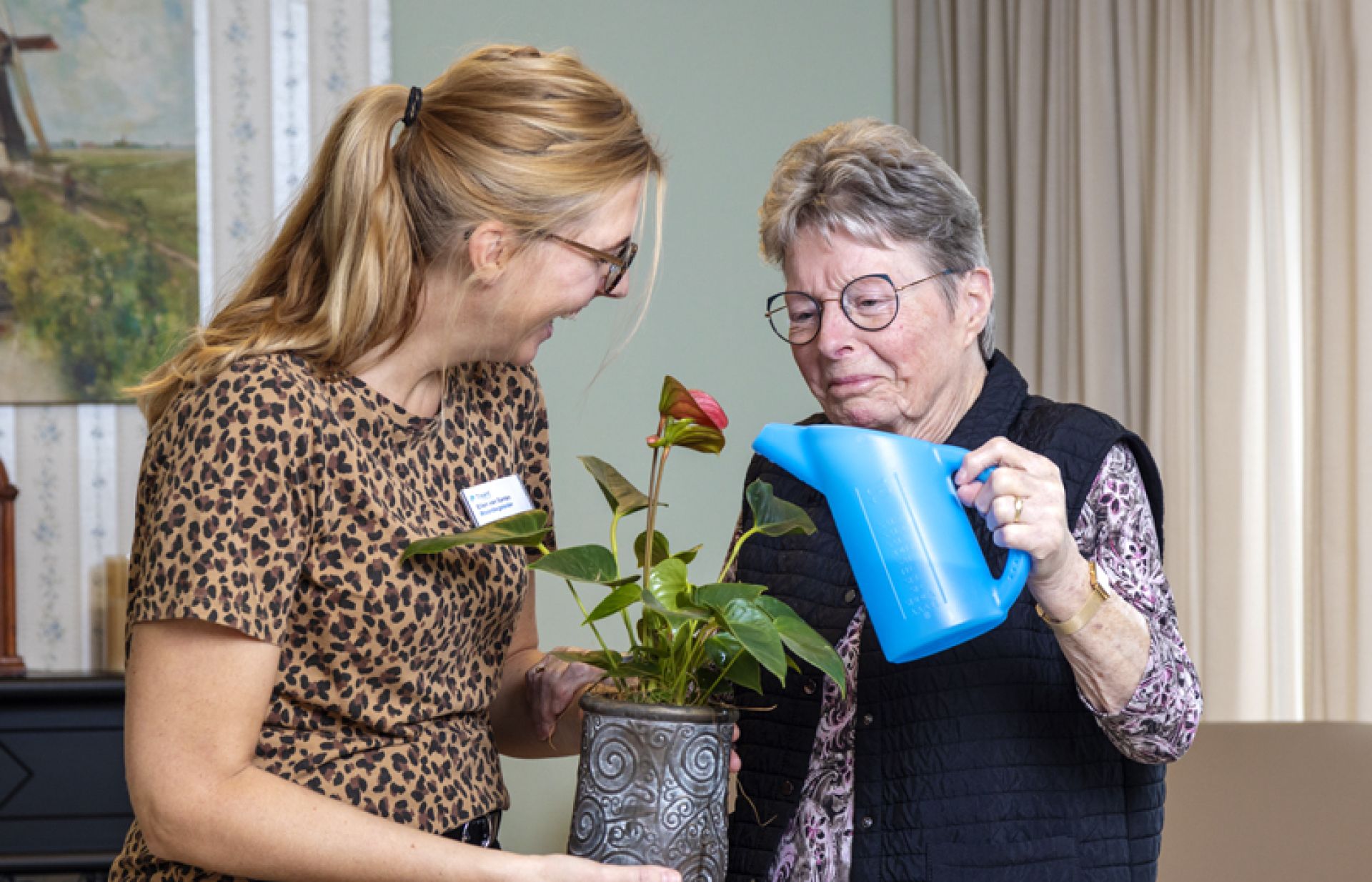 Cliënt voorziet de plantjes van water onder leiding van een medewerker.