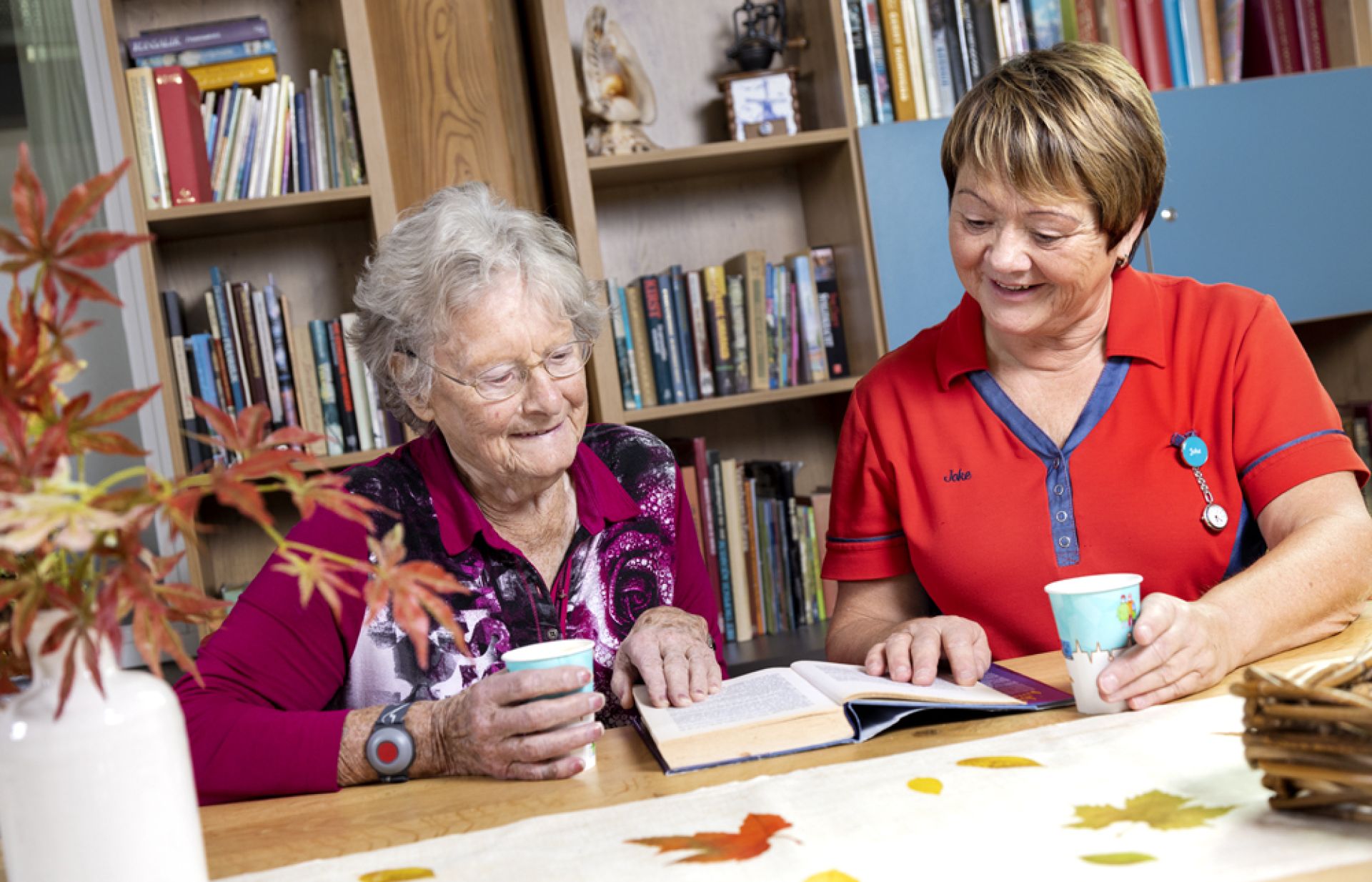 Een bewoonster en een medewerker bekijken samen een boek